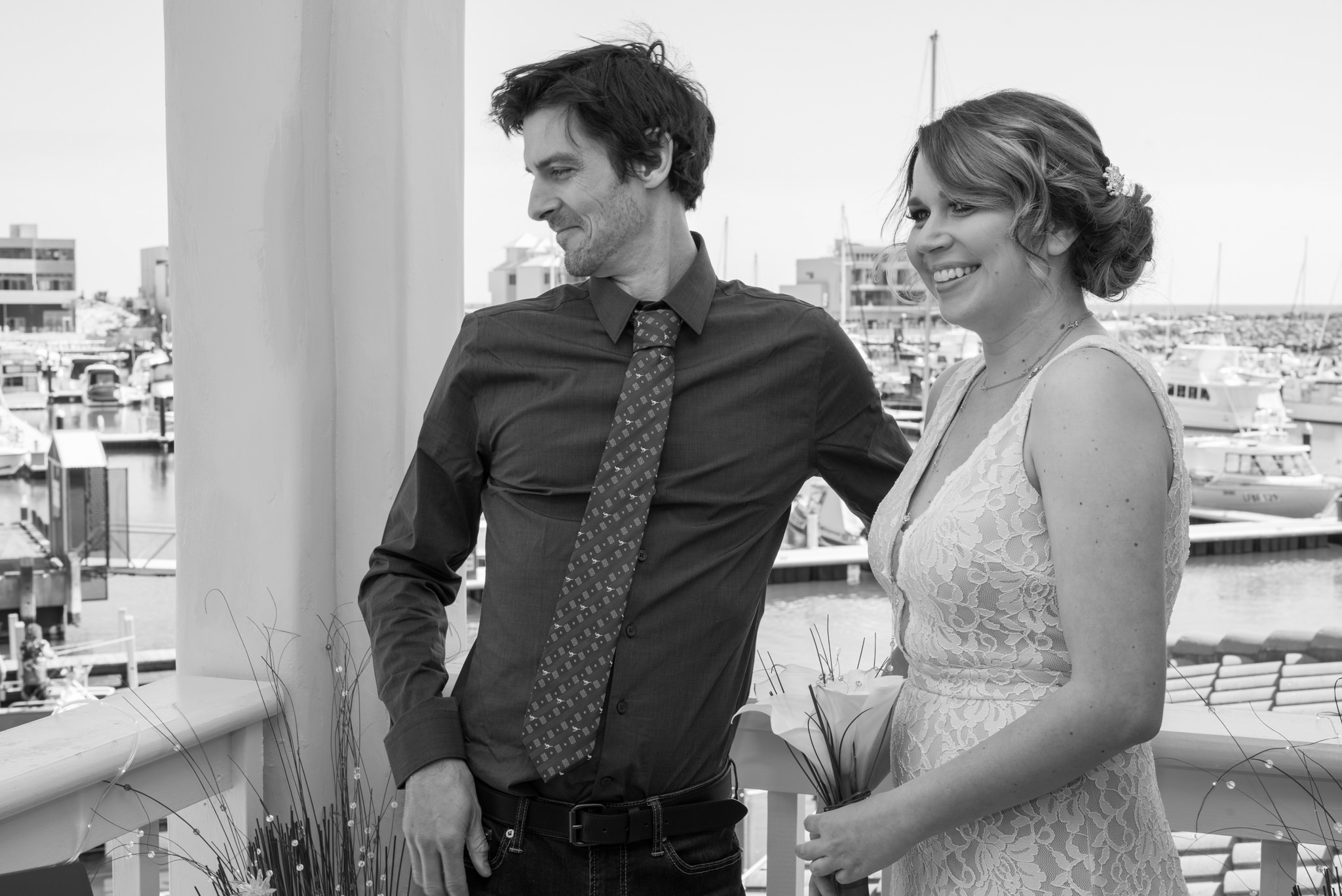 Groom looks over the balcony of their villa at Mindarie marina