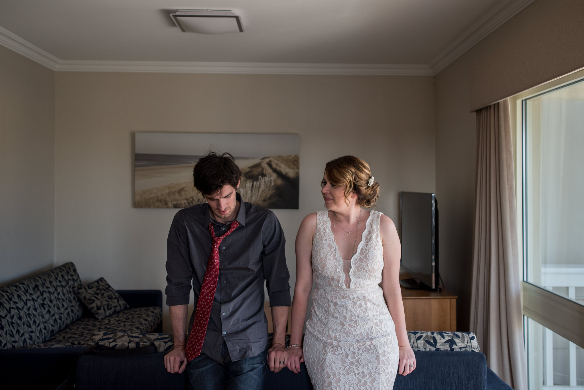 Bride and groom rest on the back of the couch in their villa after the ceremony