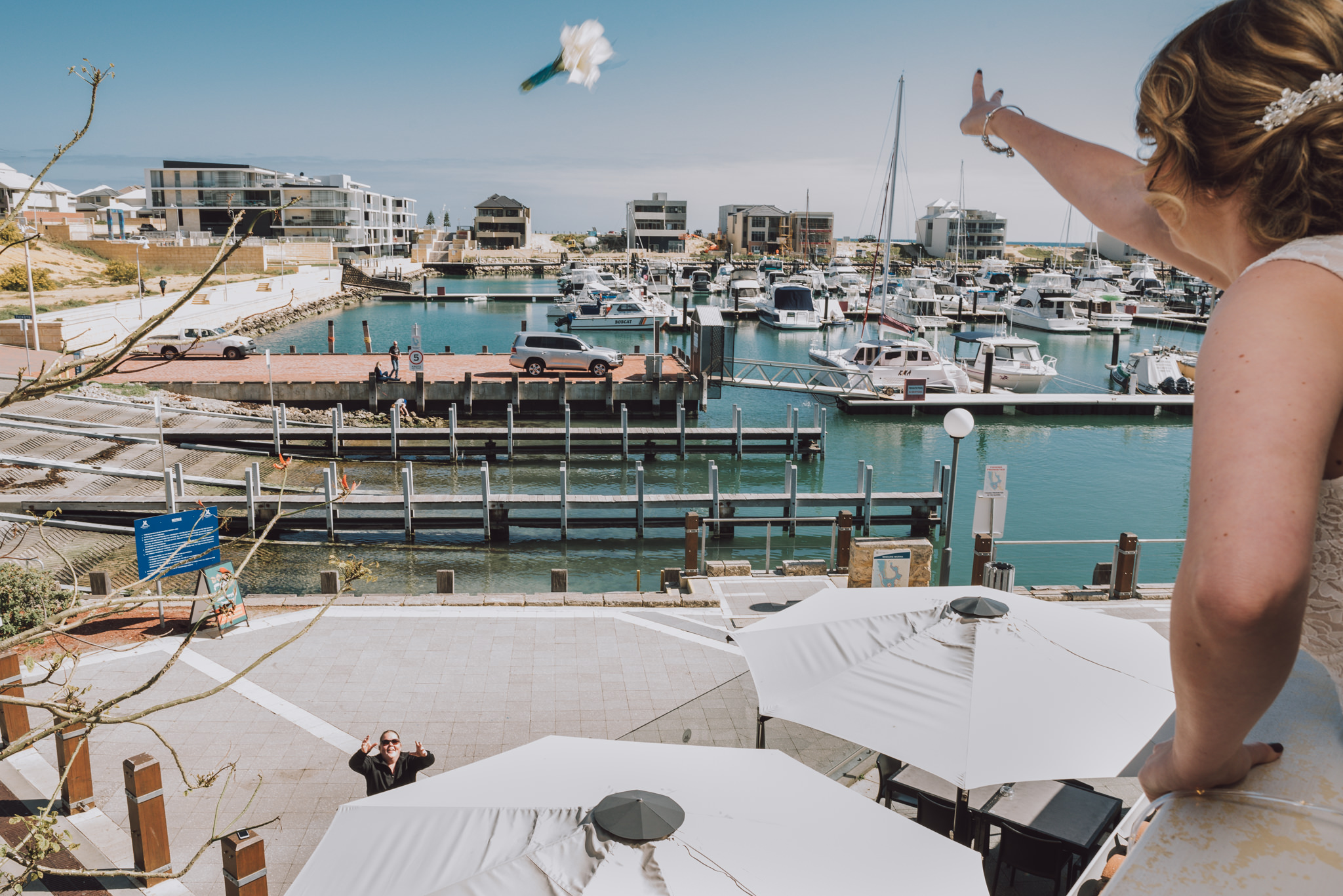 Bride tosses her bouquet to a stranger out the balcony window at Mindarie Marina