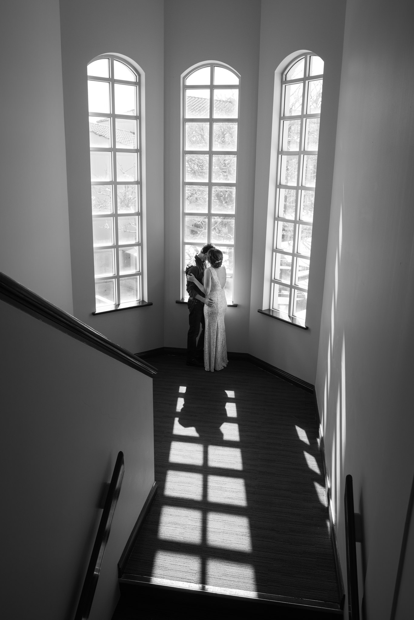 Graphic black and white photo of bride and groom cuddling in the tall window's of Mindarie Marina staircase