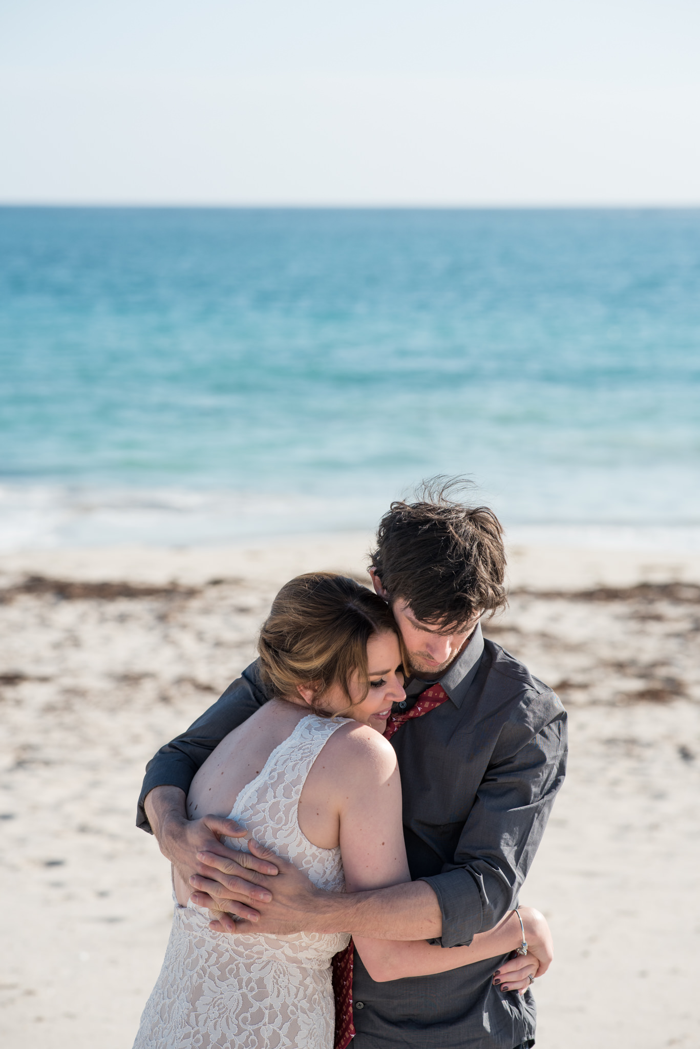 Groom cuddling bride close on Mindarie beach