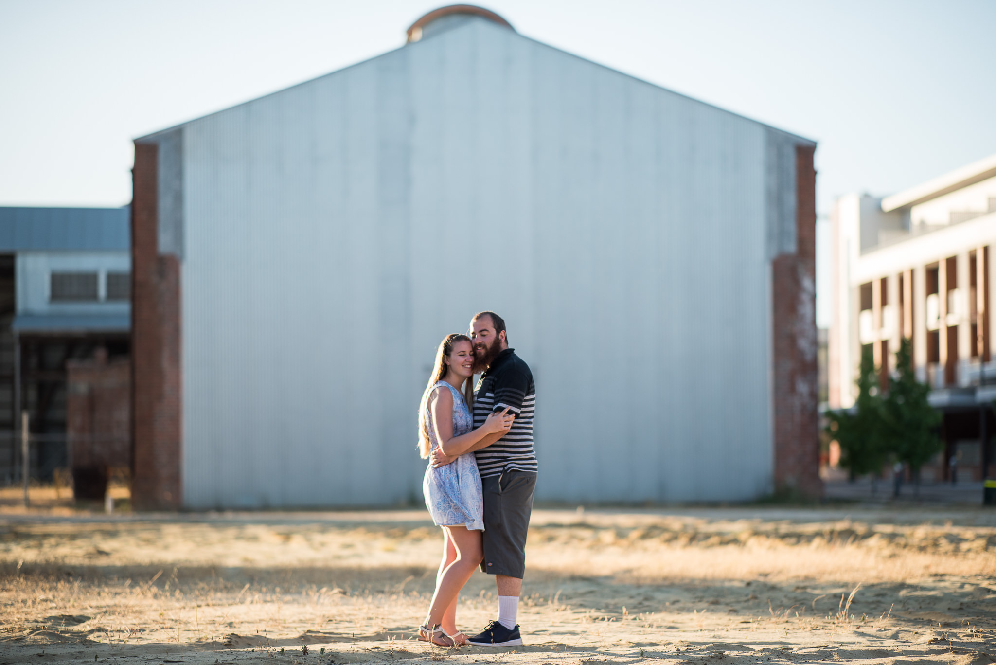 cuddling couple in front of large iron shed