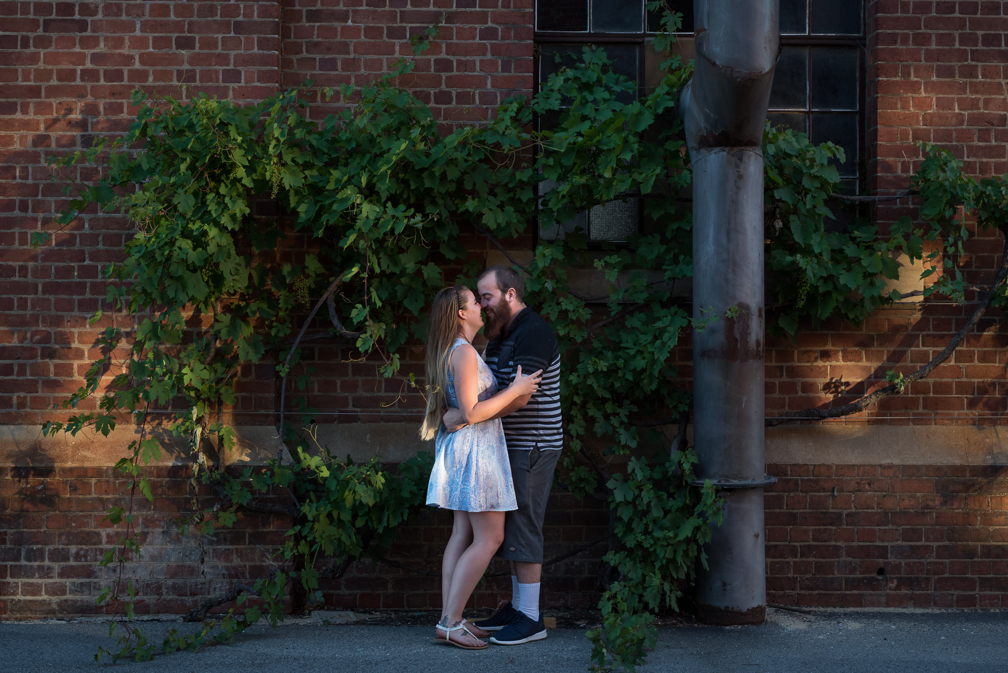 young couple cuddling at Midland Railway workshops in front of vines