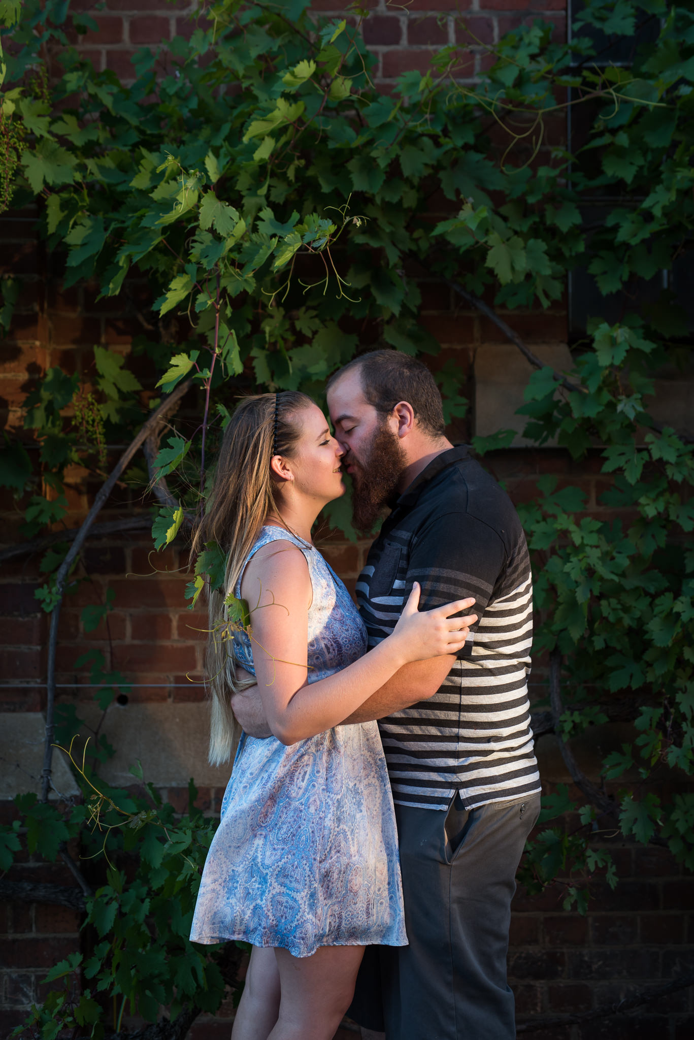 girl and boy cuddling infront of wild grape vine