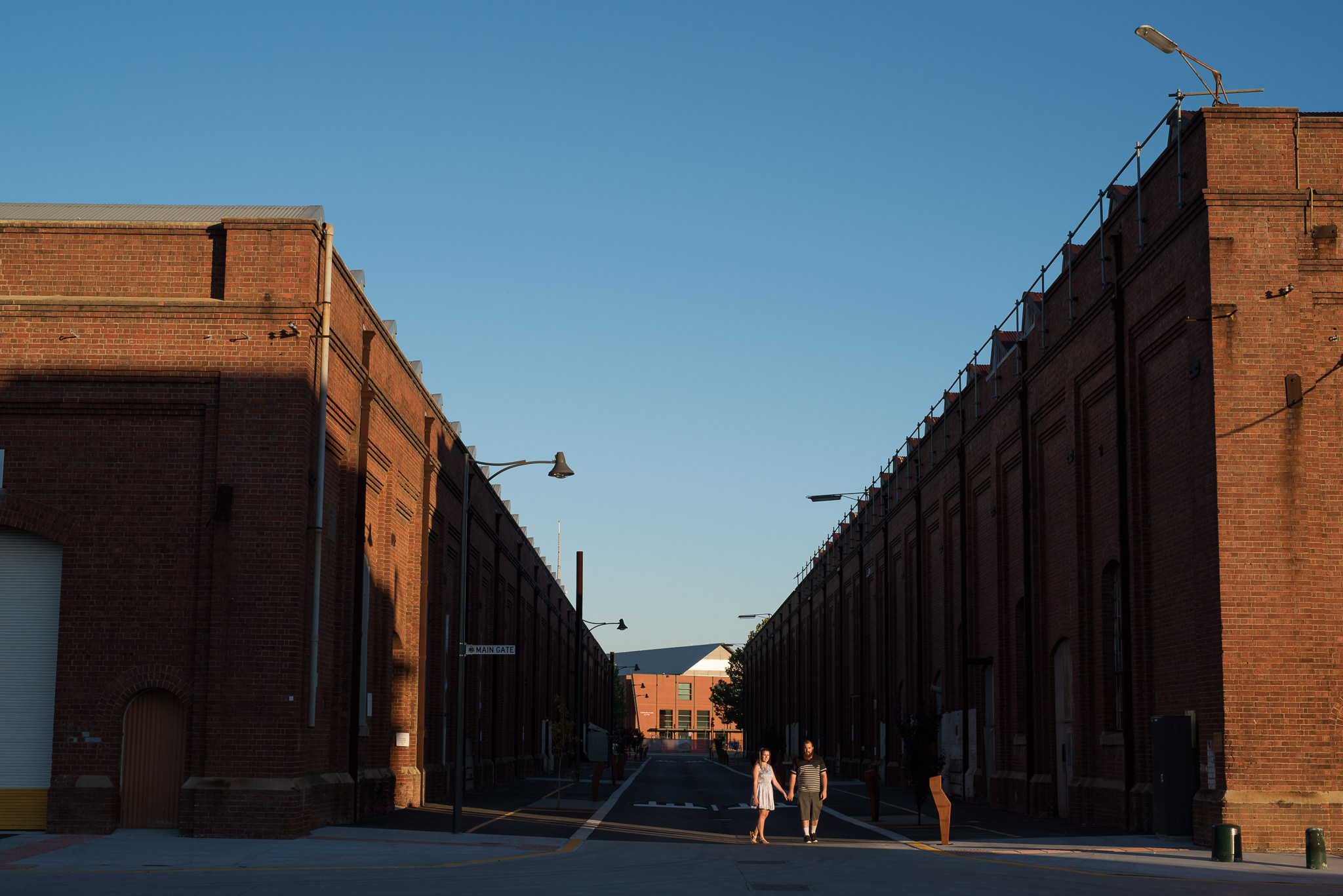 engaged couple walking in strip of afternoon light at Midland Railway workshops