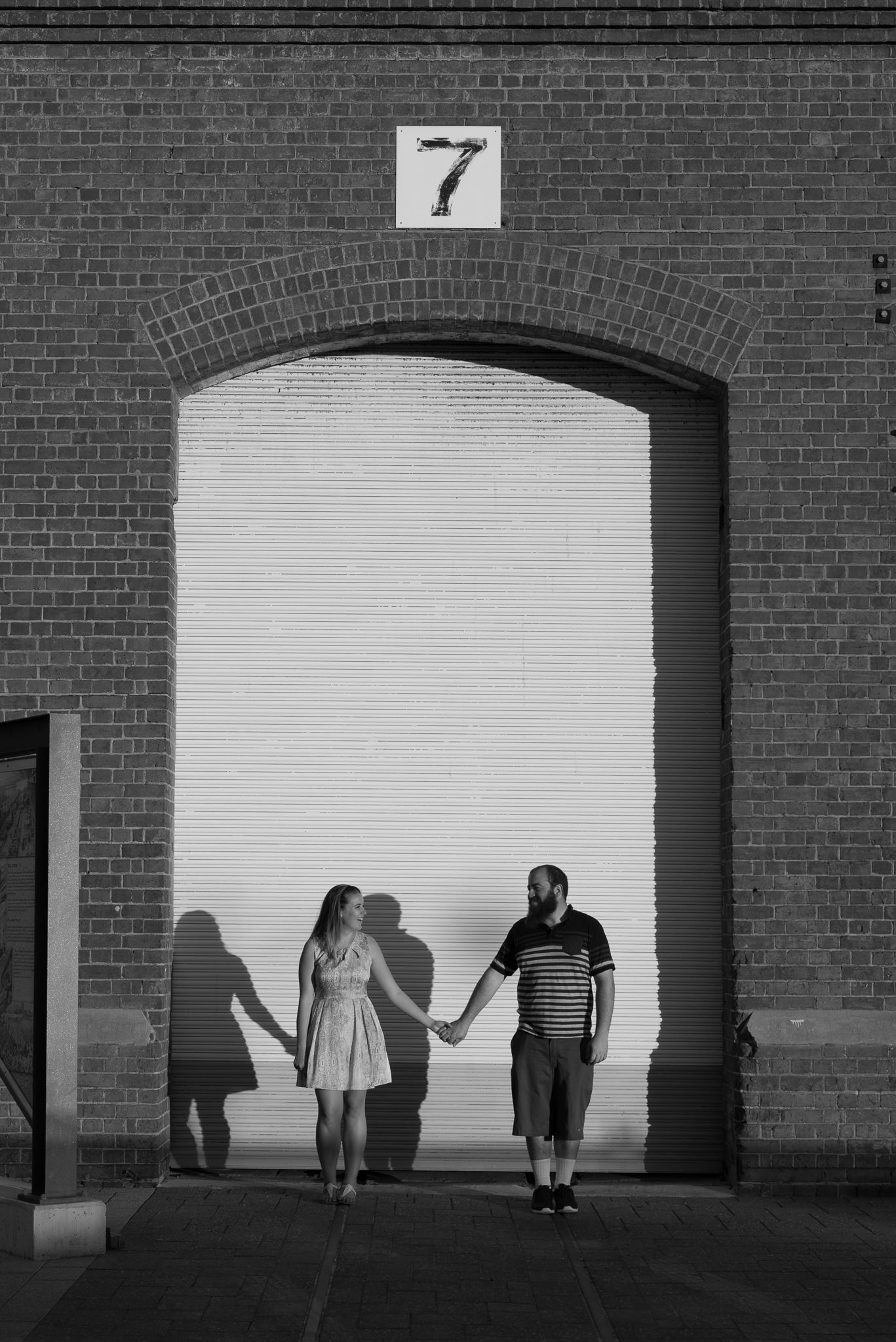 engaged couple holding hands infront of roller door at Midland Railway workshops