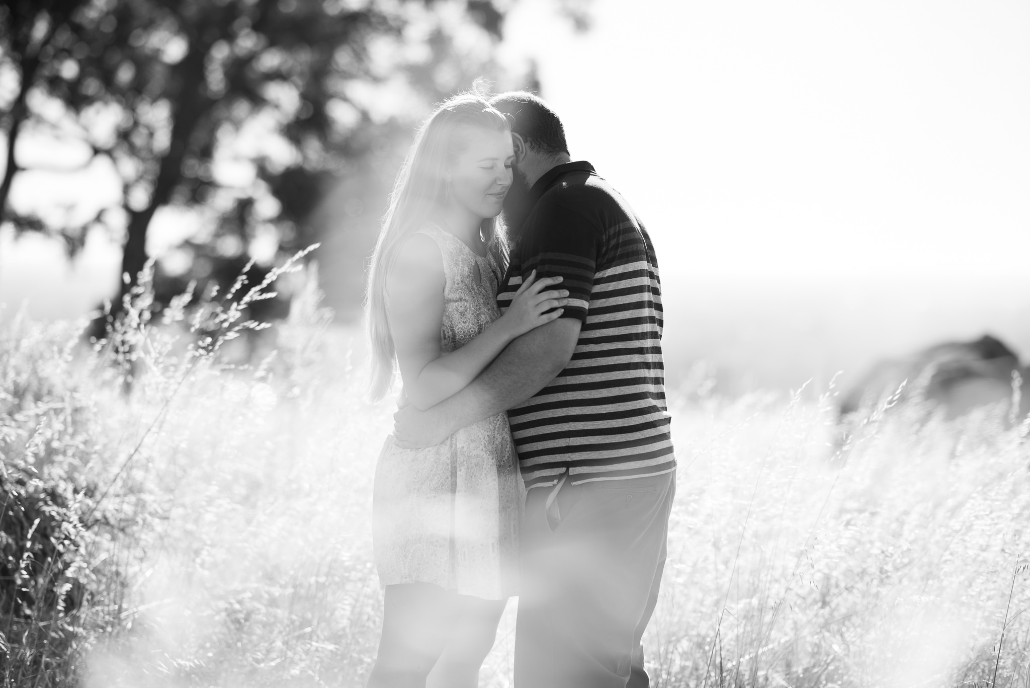 black and white photo of boy and girl hugging amongst long reeds