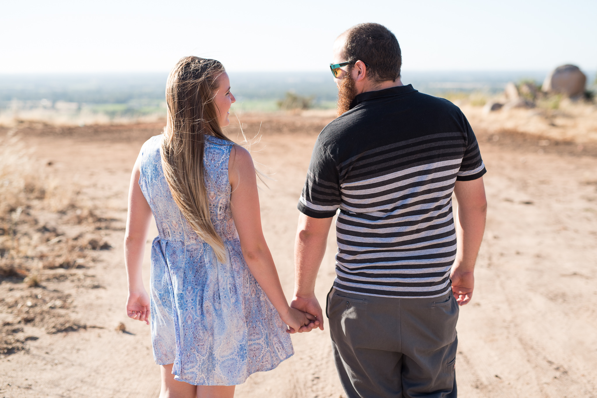 engaged girl and boy walking hand in hand away from camera