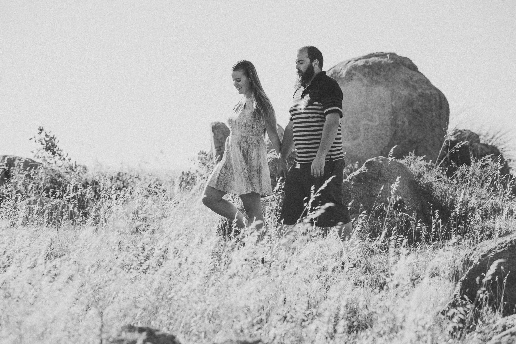 young engaged couple walking amongst boulders in the bush