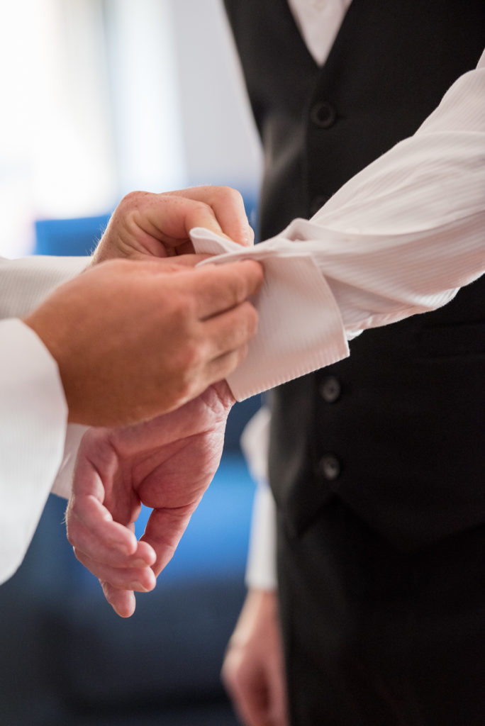 groom having his cufflink put on