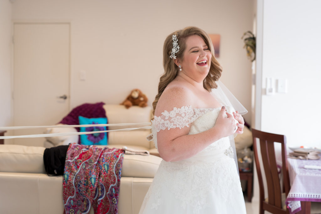 bride having her wedding dress straps pulled tight laughing