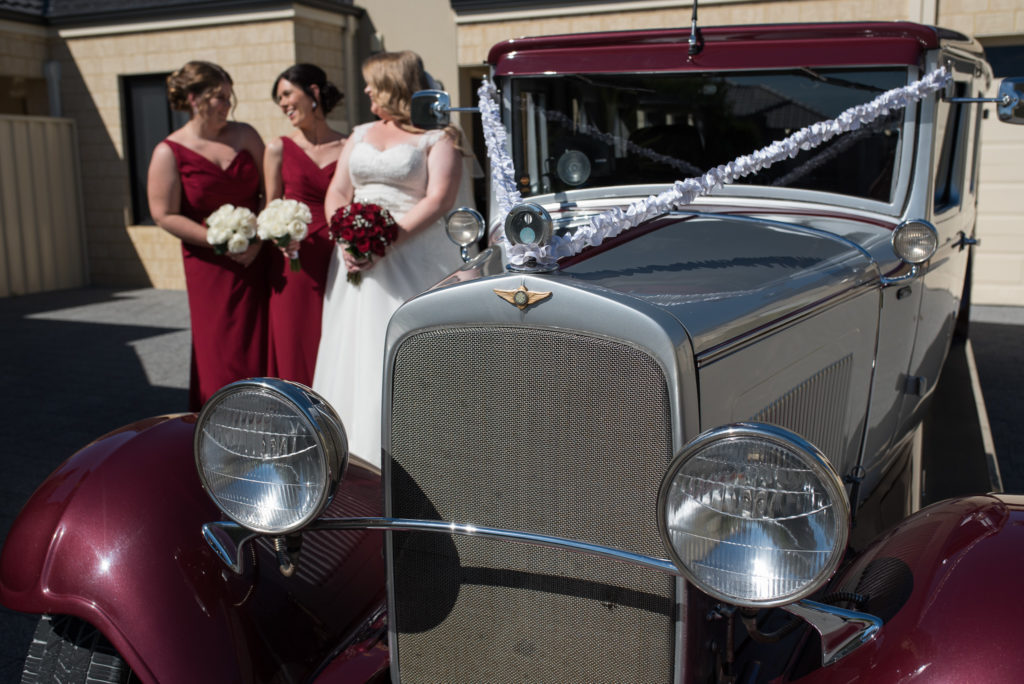 bride and her bridesmaids and their vintage wedding car