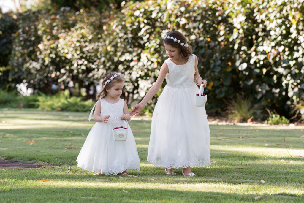 two flower girls walk down the aisle on the grass