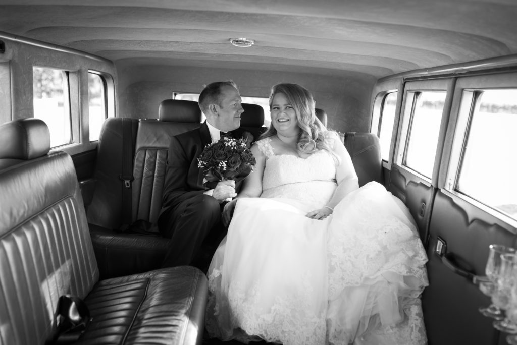 groom looking at bride inside vintage wedding car