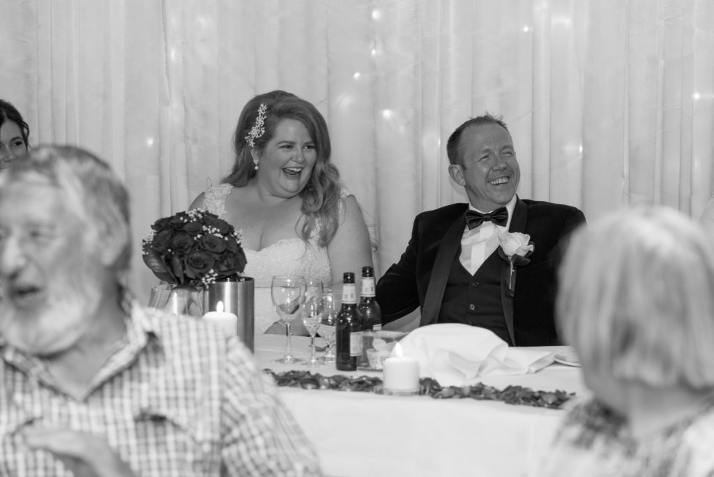 Bride and groom laughing at the speeches