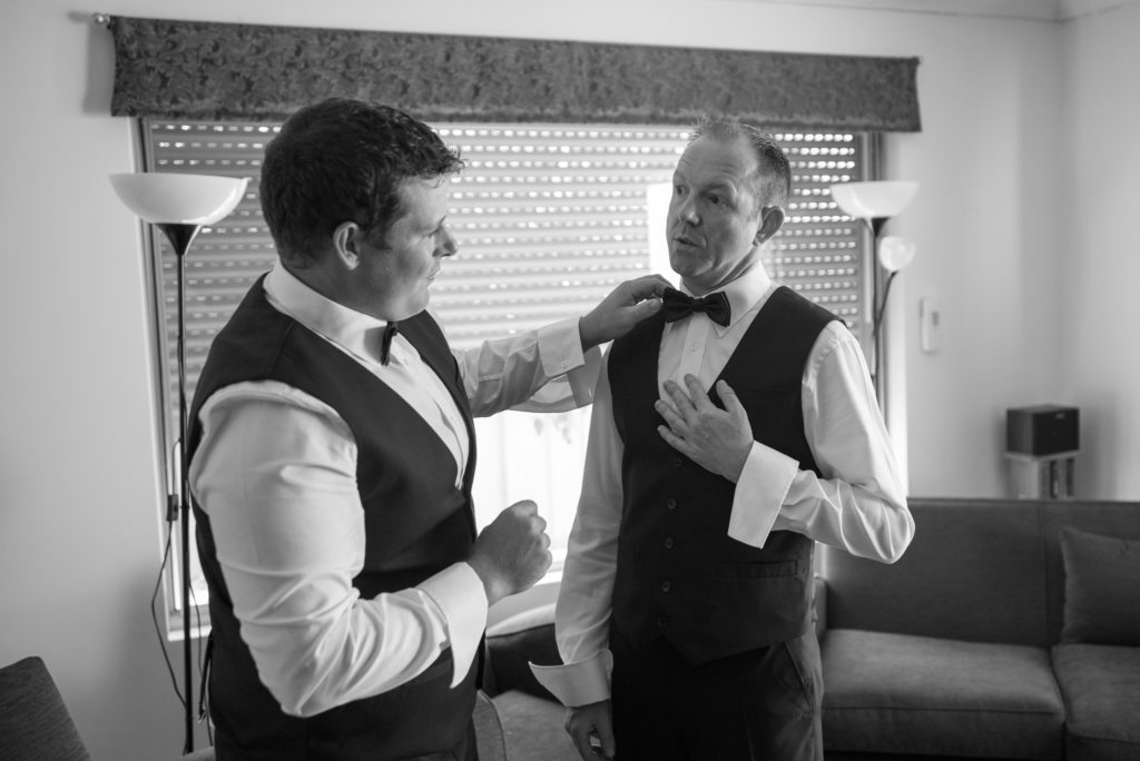 groom having his bowtie adjusted