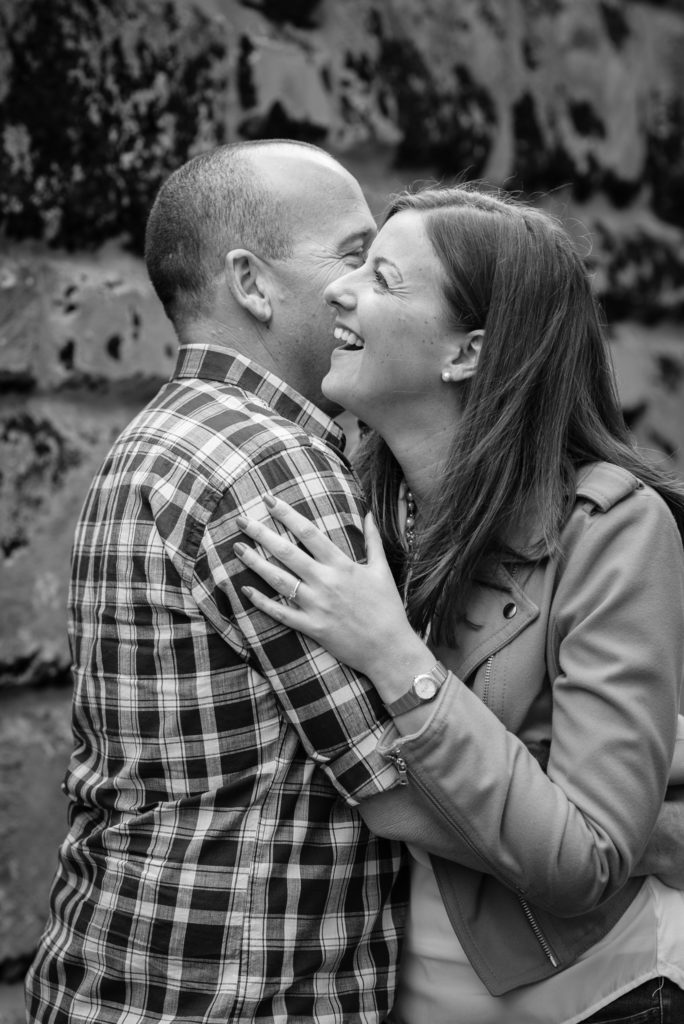 guy whispering into his fiancee's ear and she is smiling