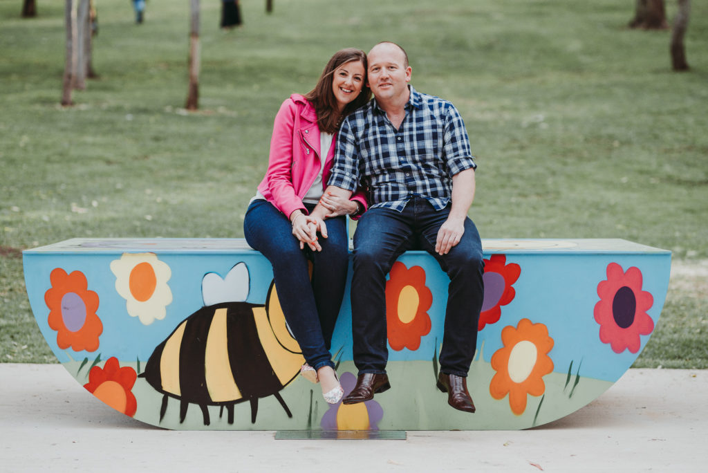 engaged couple sitting on kids play equipment