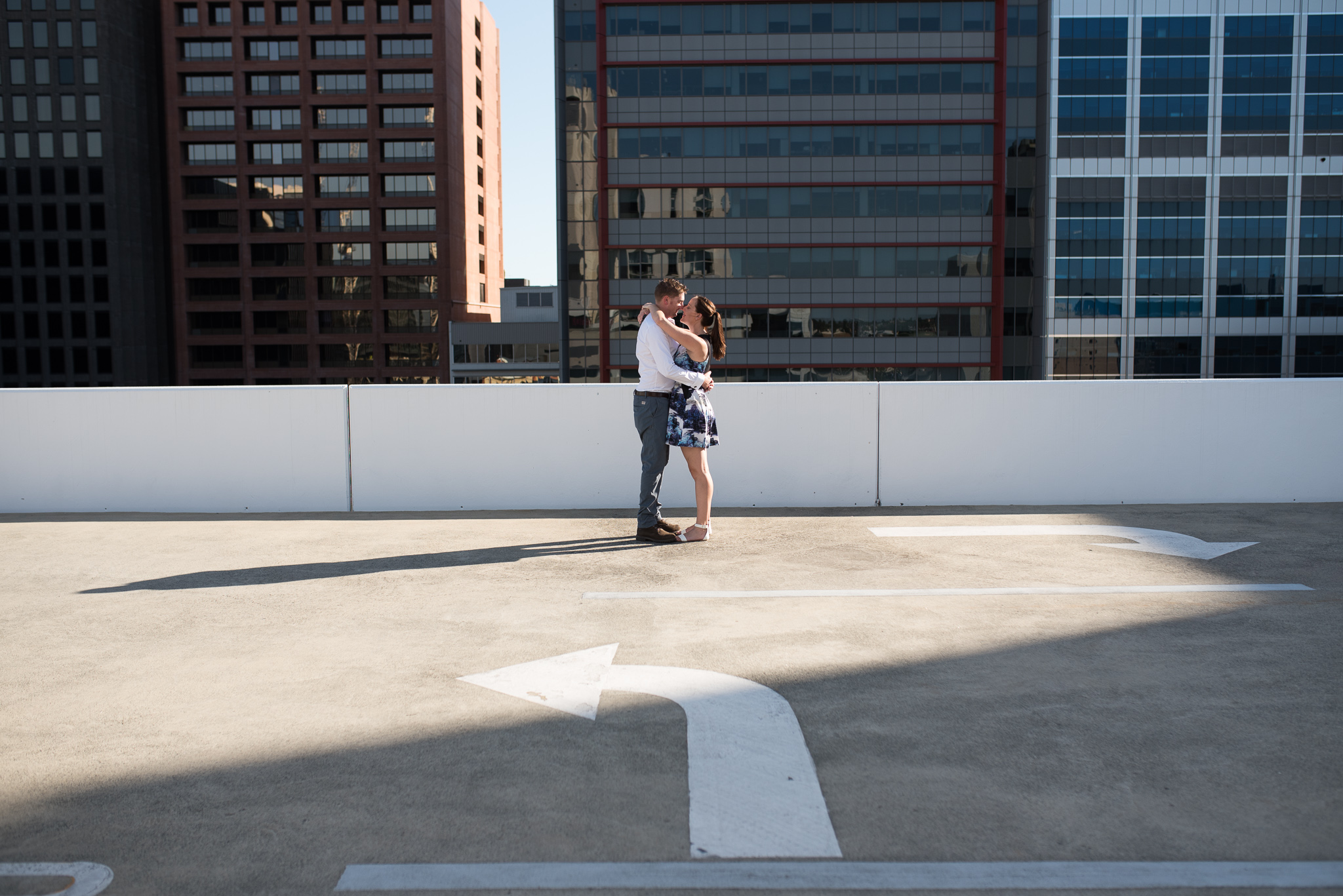 Urban city carpark rooftop portrait of engaged couple with left turning arrow