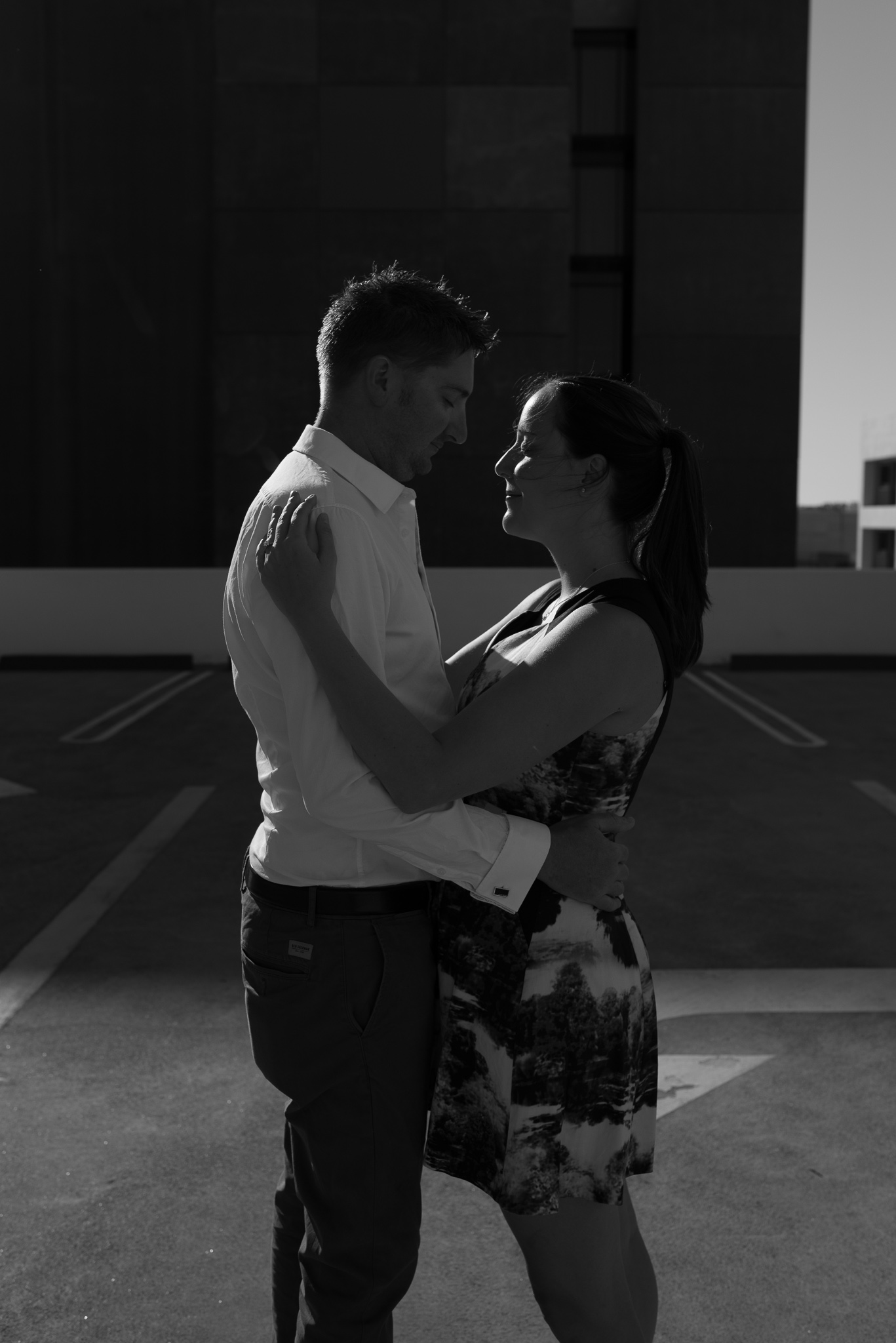 Very low key B&W portrait of engaged couple on carpark rooftop