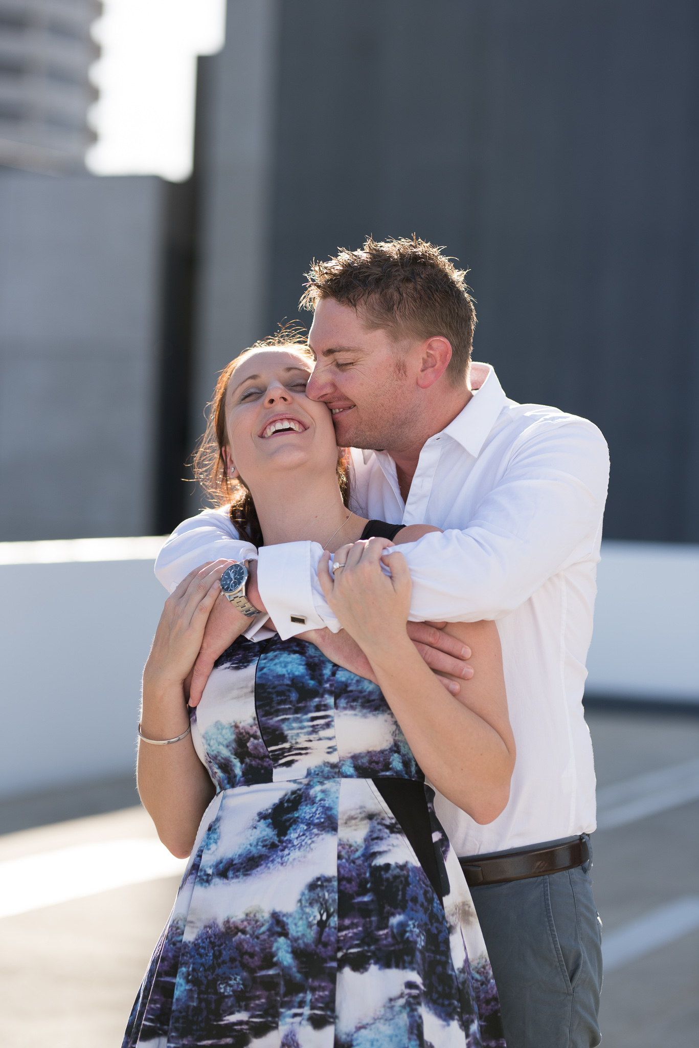 Boy hugs his fiancee during carpark rooftop engagement session