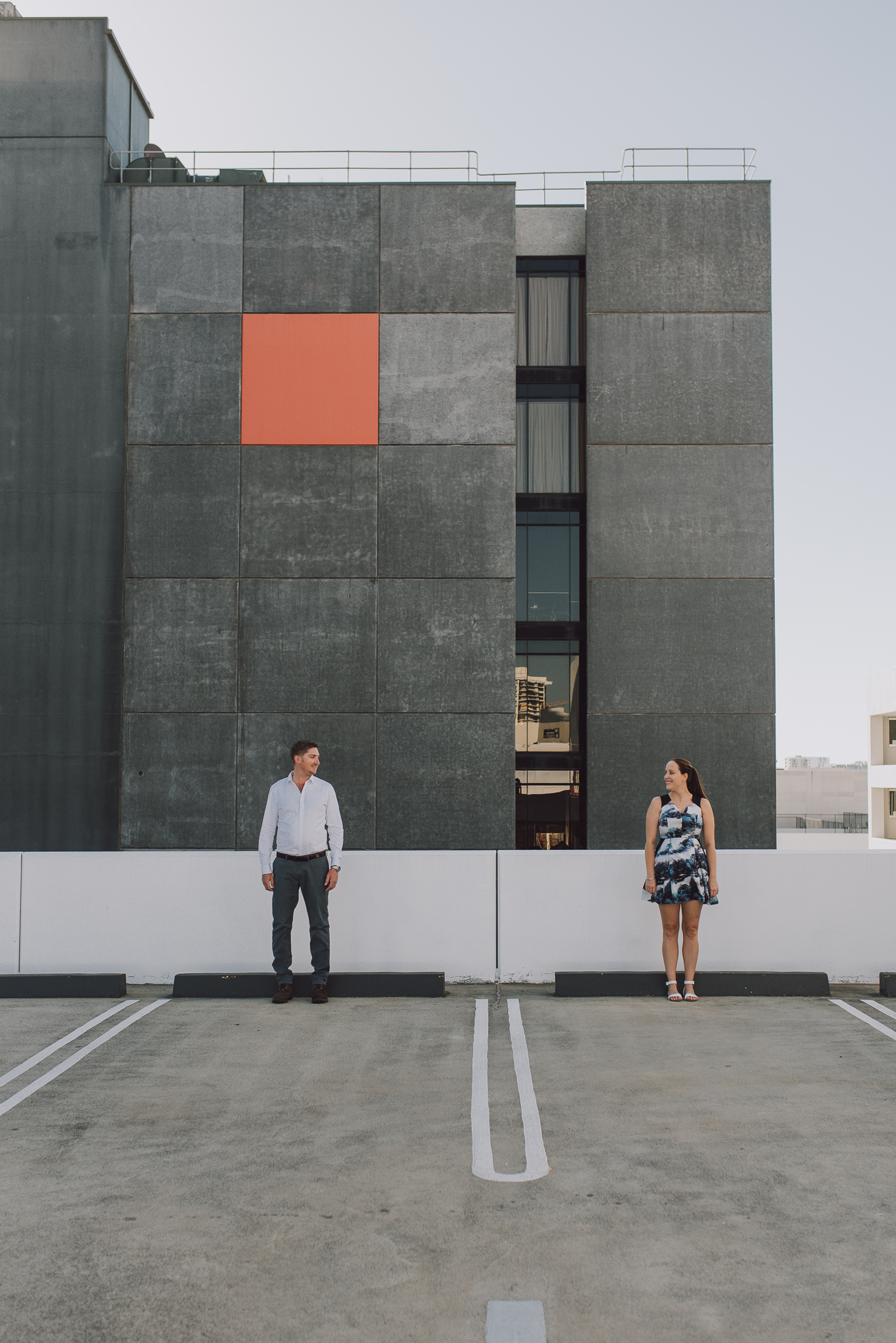 Red square on Perth city building with engaged couple standing apart on carpark roof top