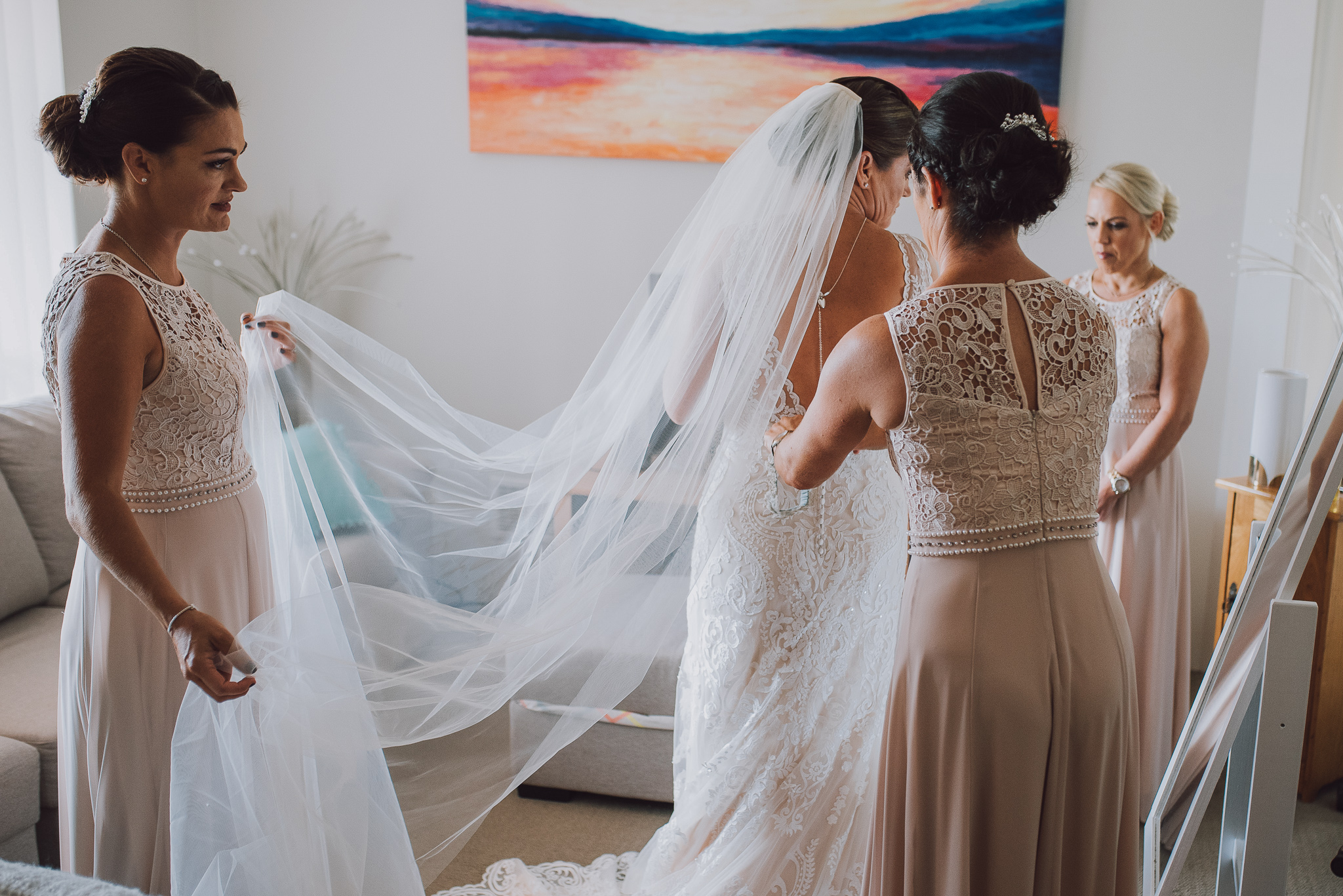 bride has her dress done up with her veil