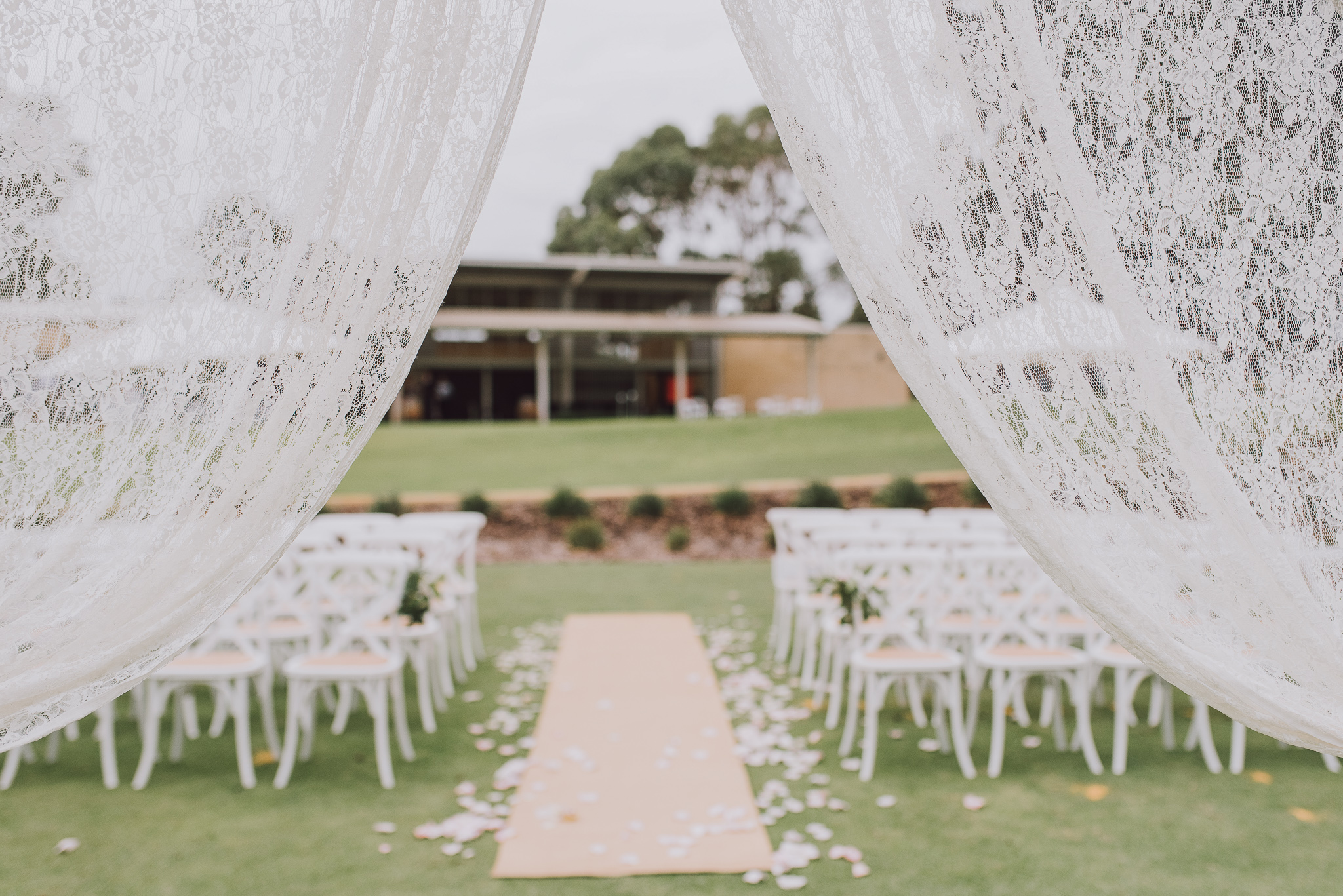 View of wedding ceremony setup through the lace curtains at Point Walter golf course