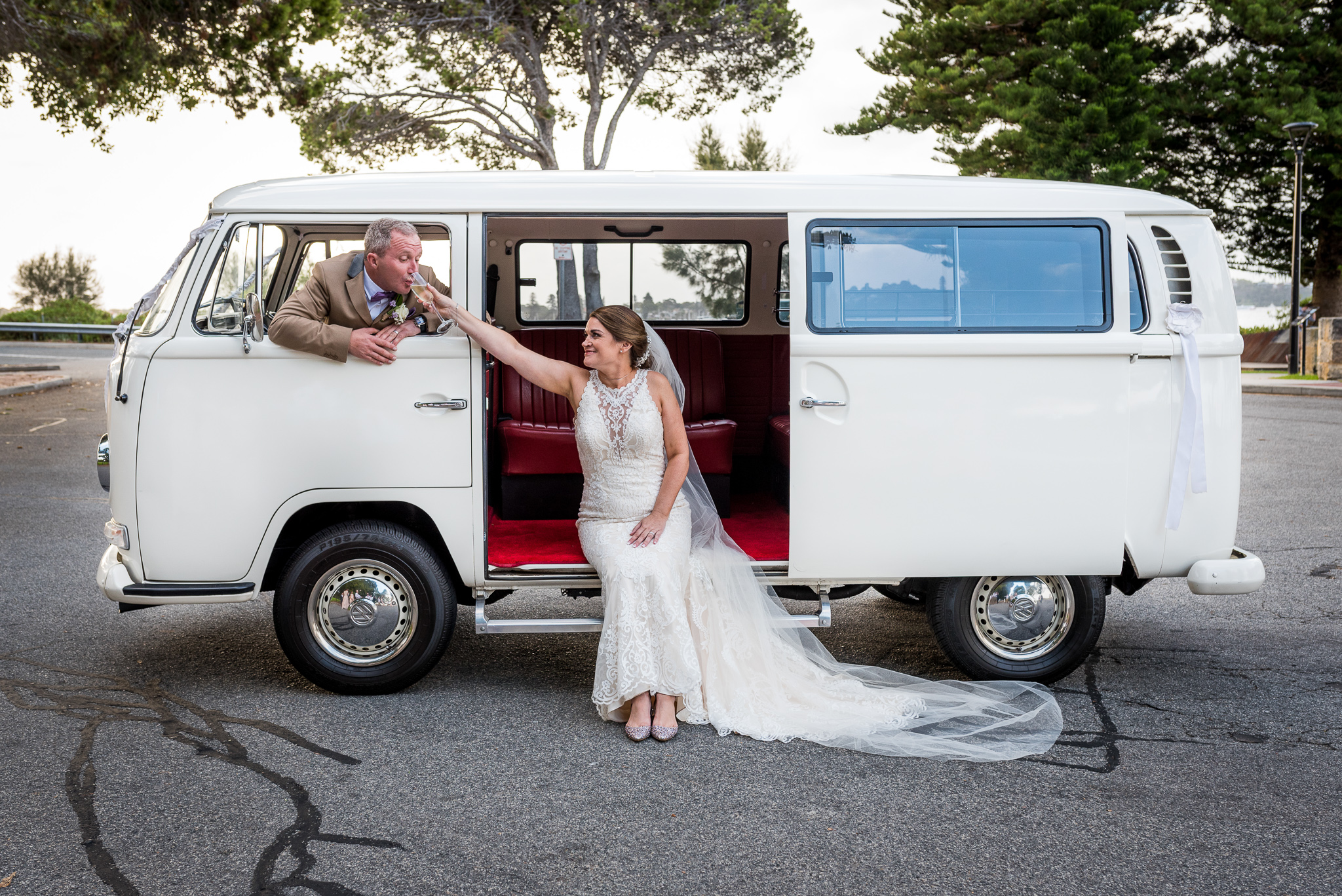 bride gives groom champagne to sip out his kombi window