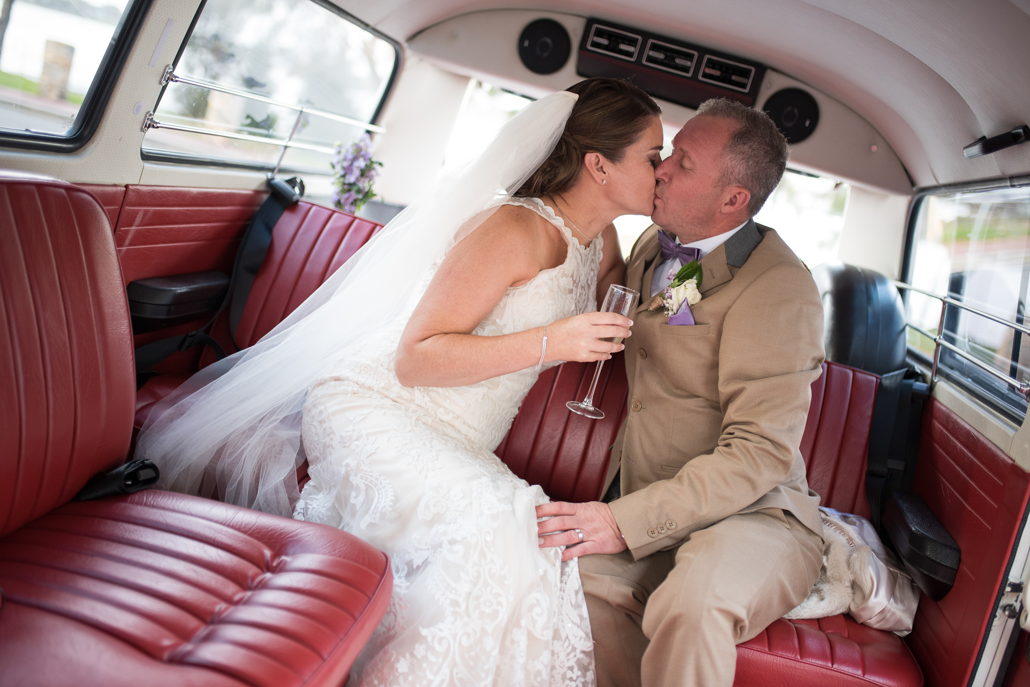 bride and groom kissing in vintage kombi with red leather seats