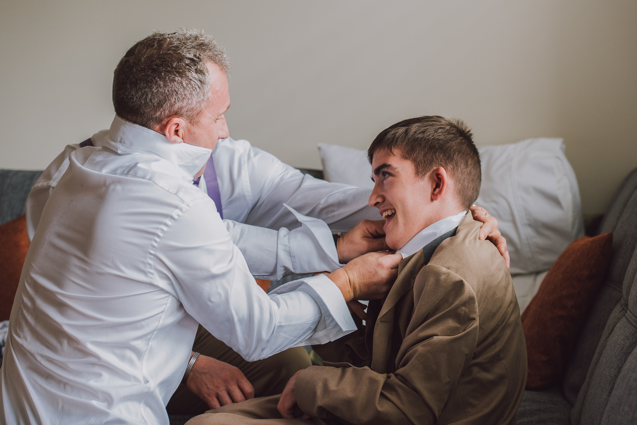 groom helps his son get dressed for wedding