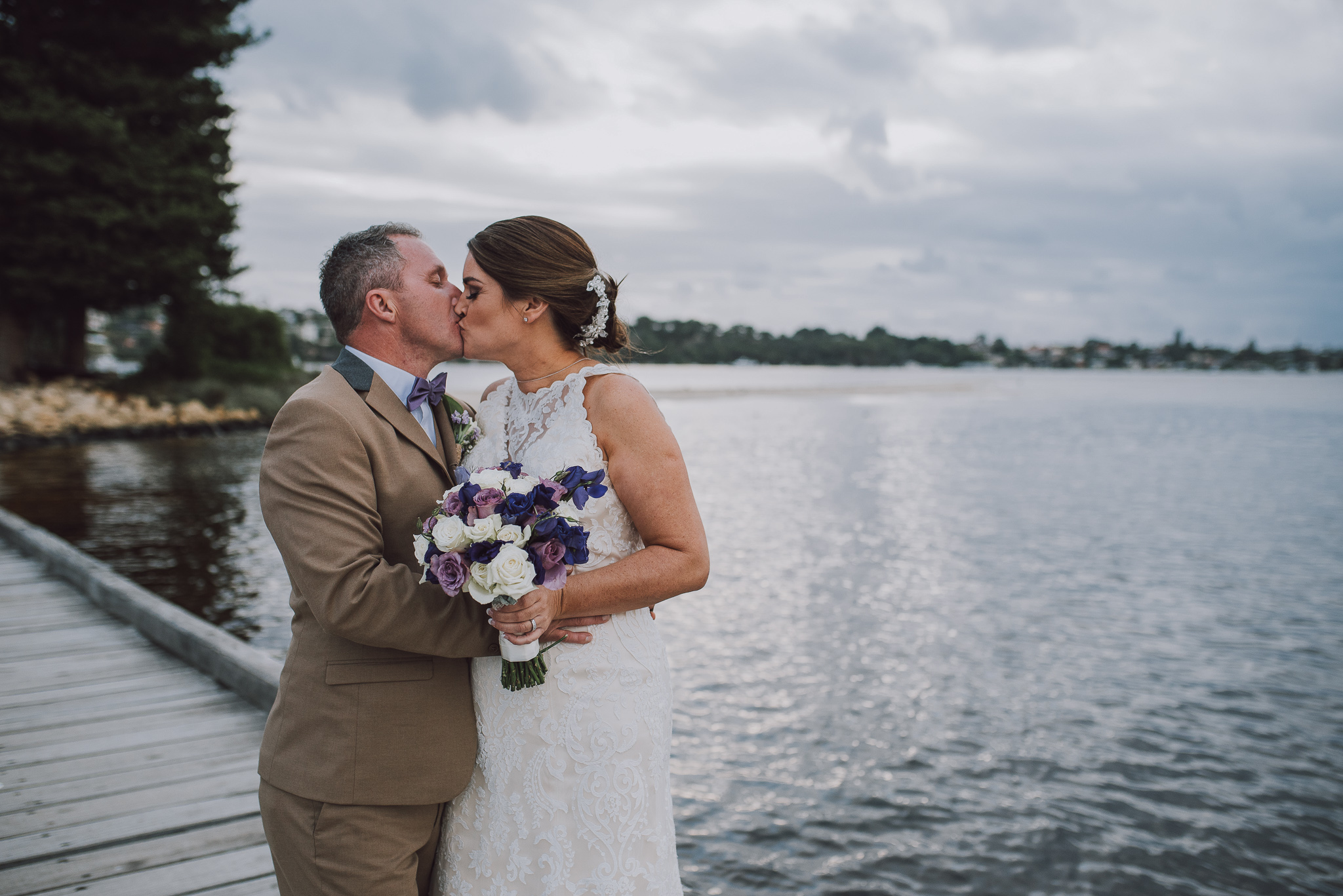 bride and groom kissing on the pier at point walter