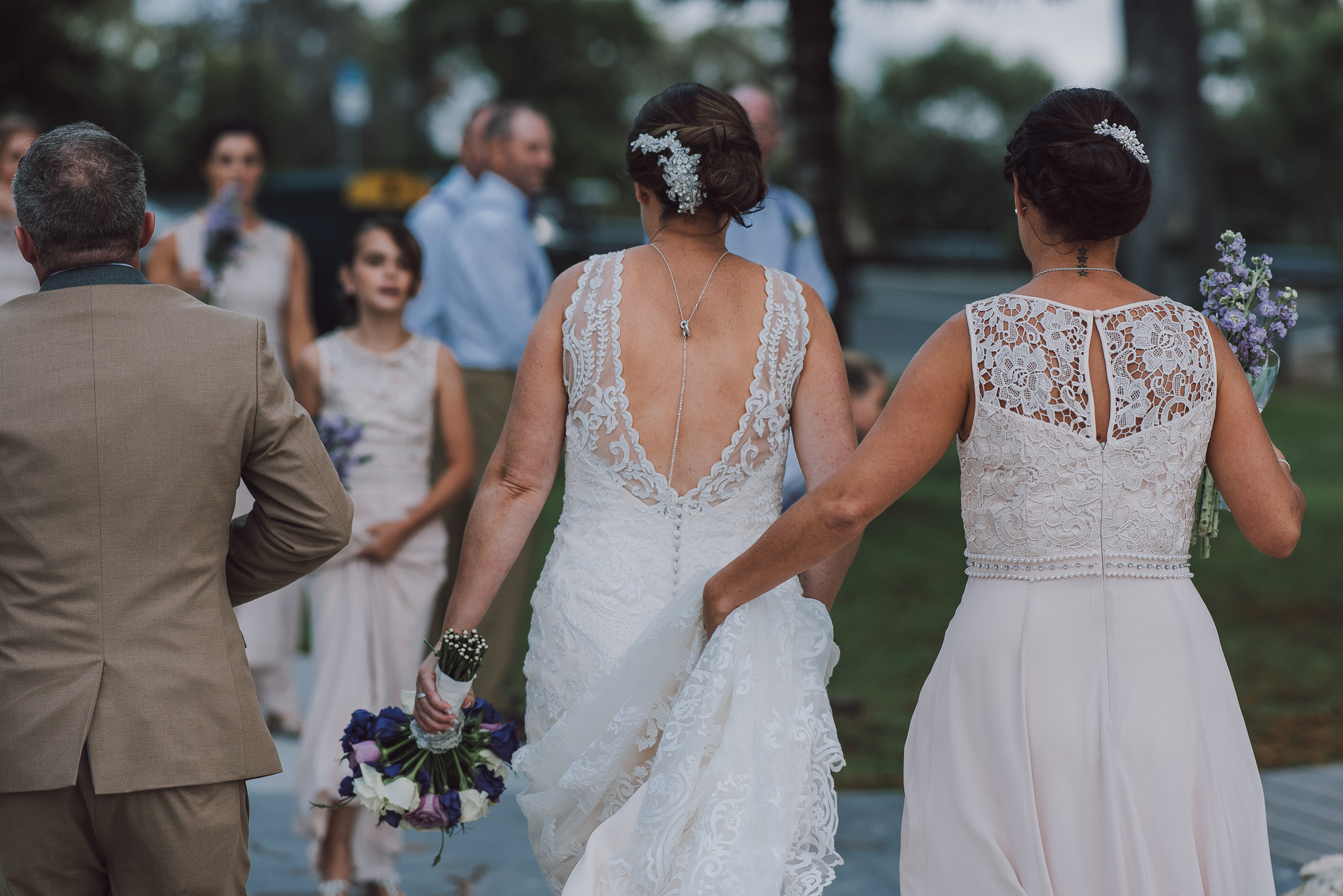 bride walking along with bridesmaid holding her dress up