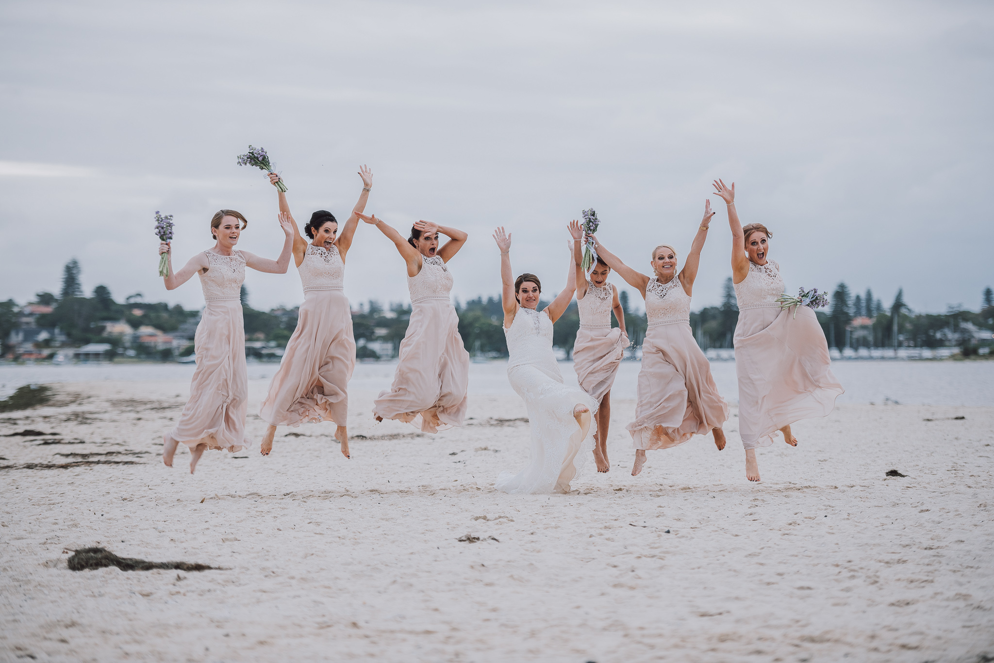 bride and her ladies jumping on the sand