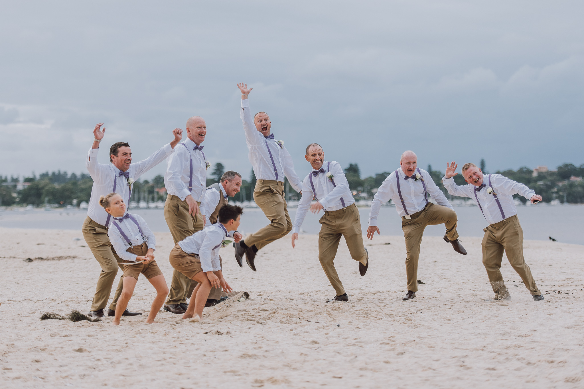 groom and his boys jumping on the sand