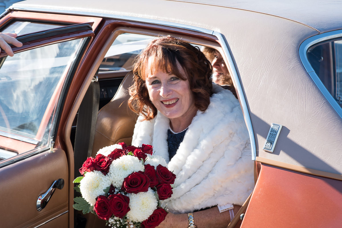 Mature aged bride stepping out of her wedding car