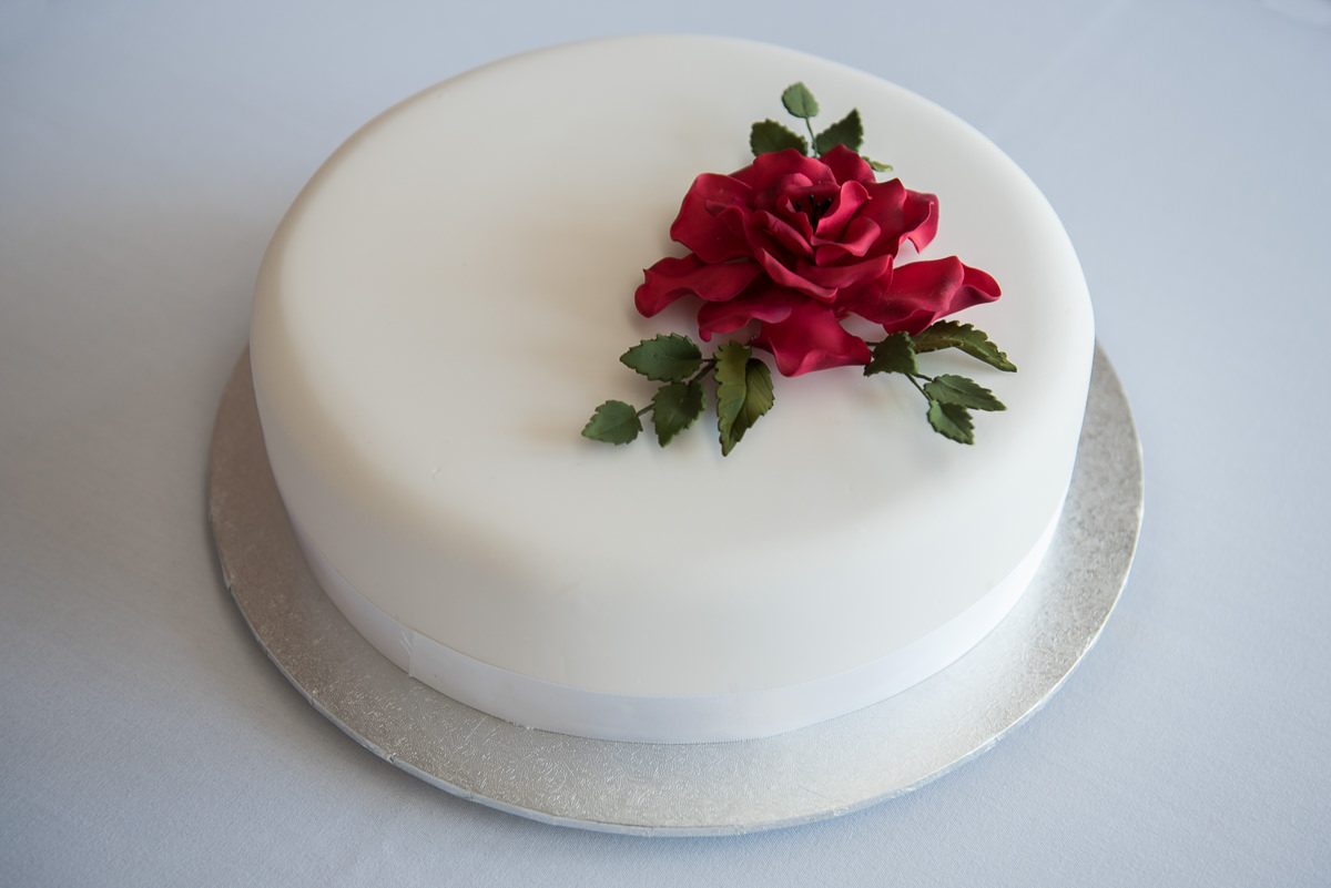 White wedding cake with red sugar flower