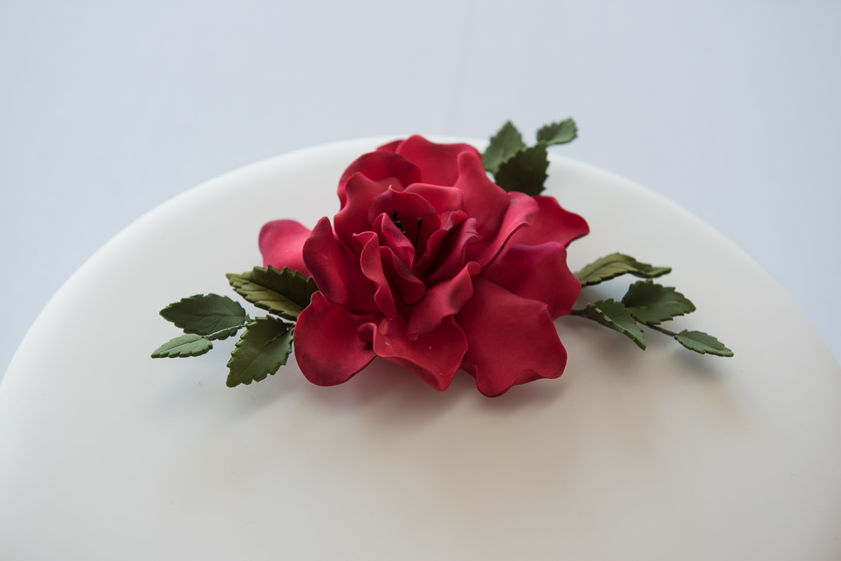 Close up of wedding cake with red flower