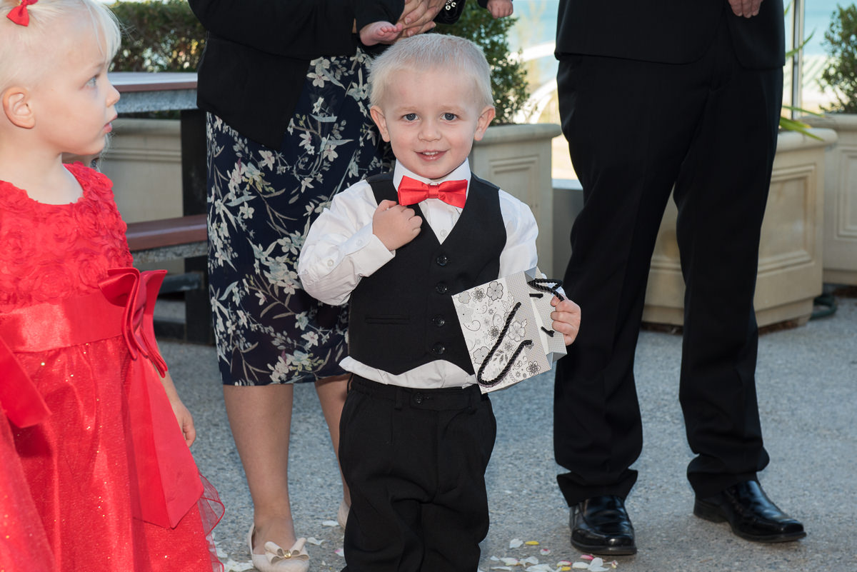 Cute photo of grandson wearing red bow-tie and black vest with white long sleeved shirt at a wedding