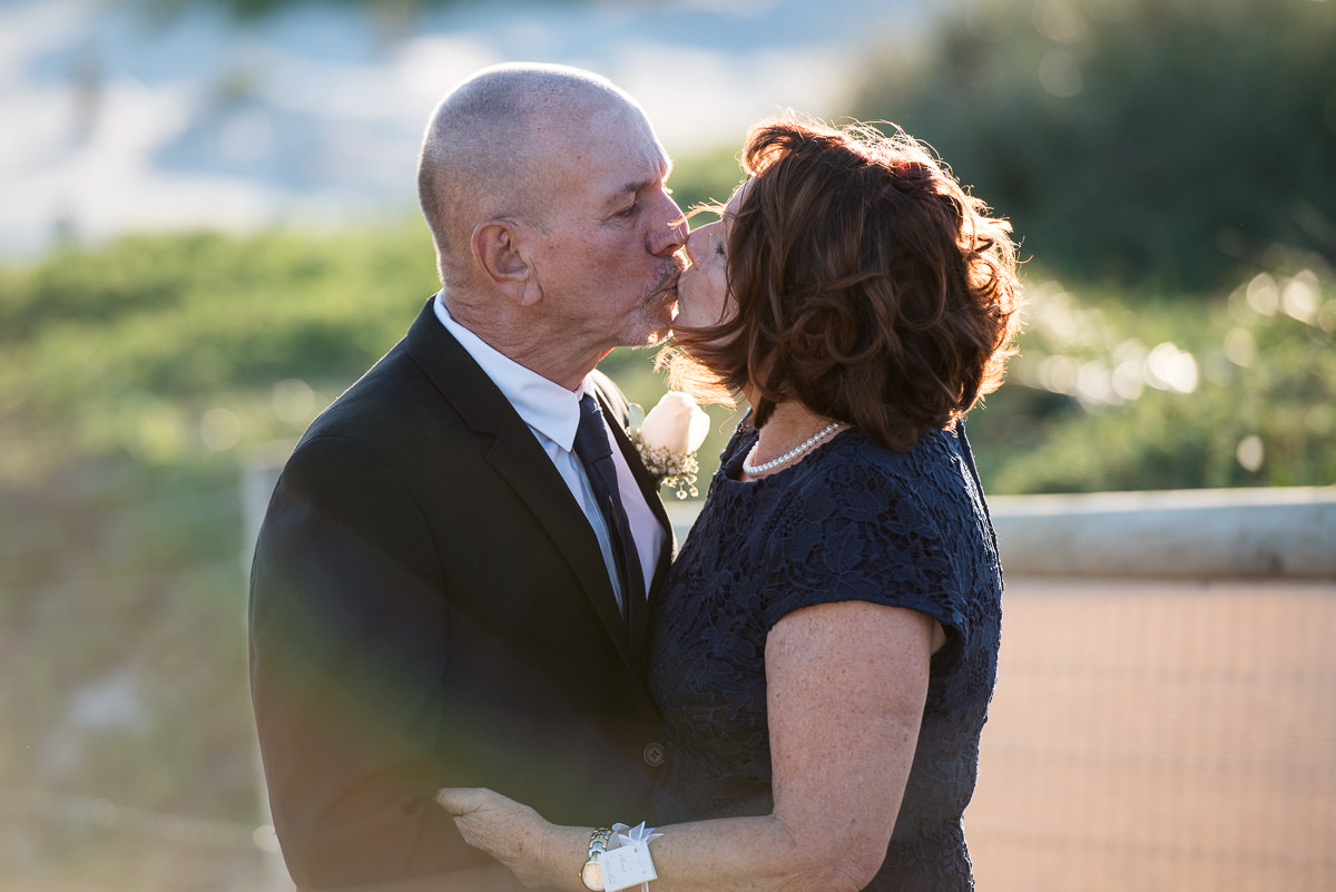 Mature aged bride and groom kissing at the beach