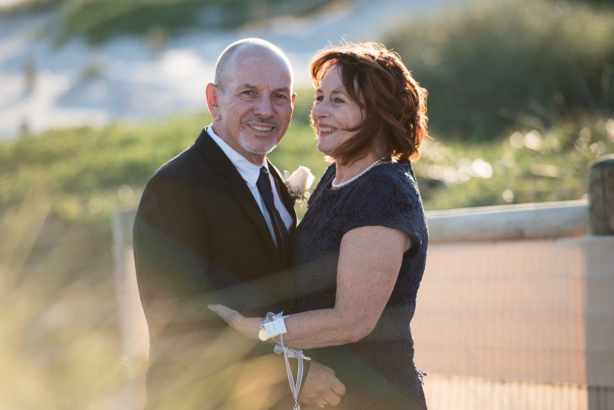 Mature bride and groom smiling at the beach