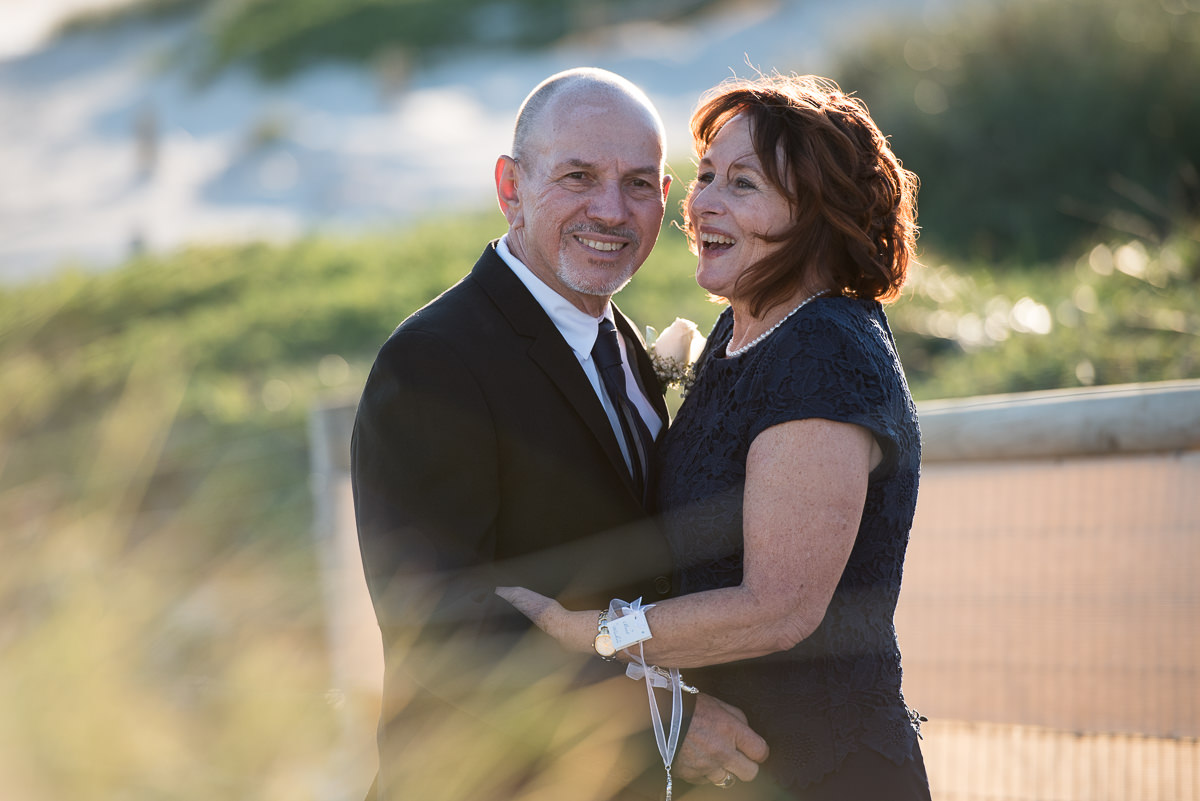 Mature-aged Bride and groom laughing at the beach