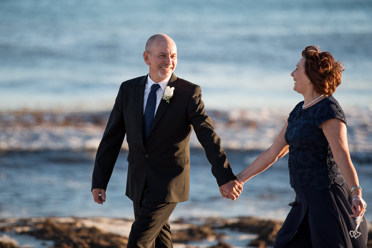 Mature wedding couple smiling and holding hands walking on Mindarie beach