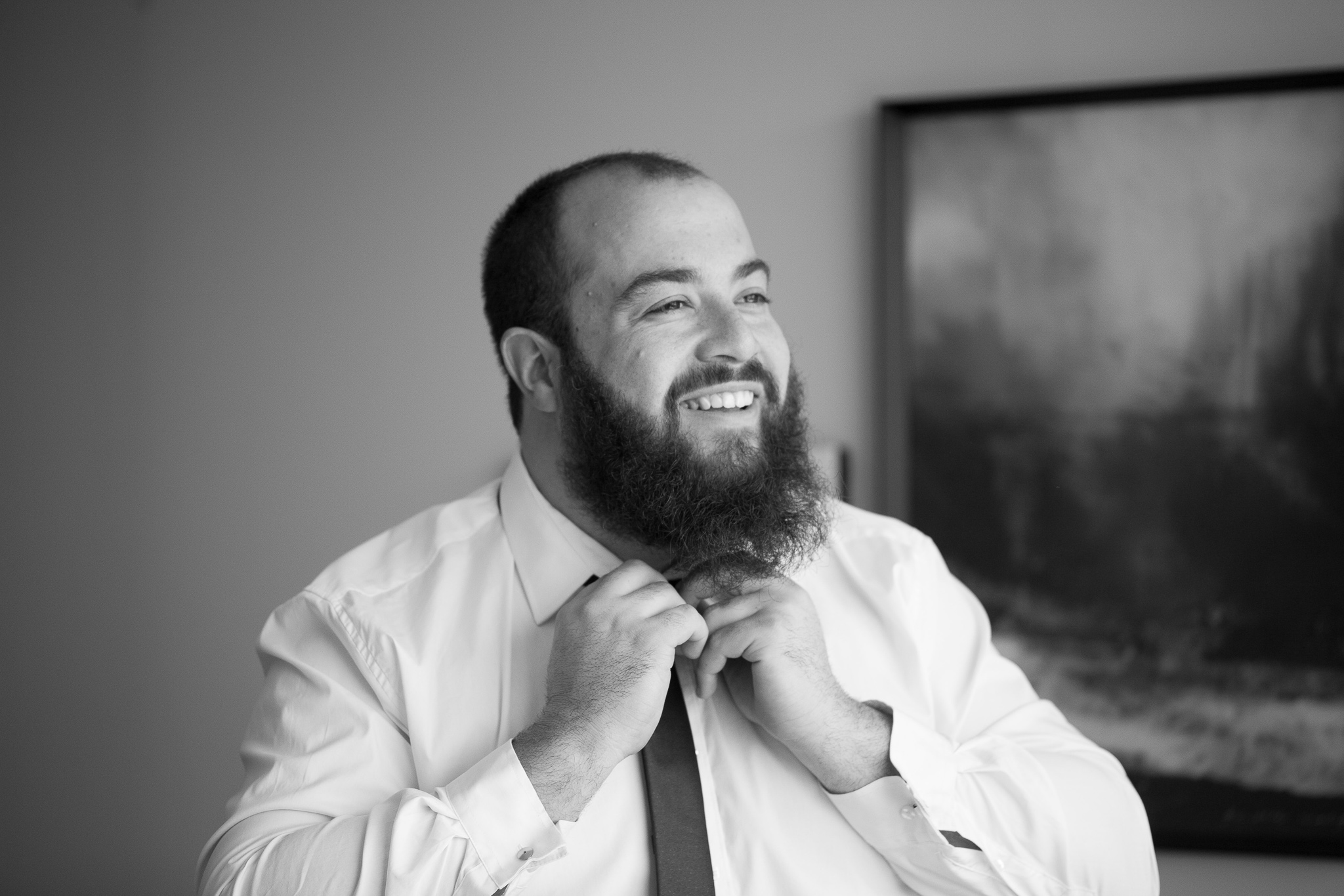 groom fixing his tie and smiling