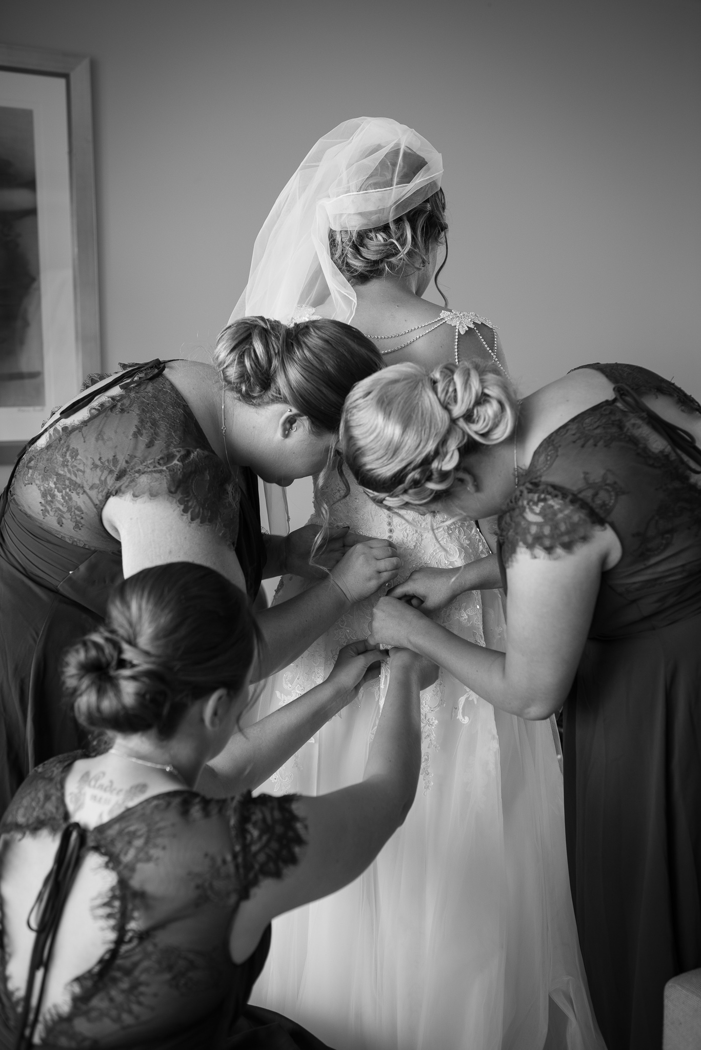 bridesmaids doing up her dress in black and white