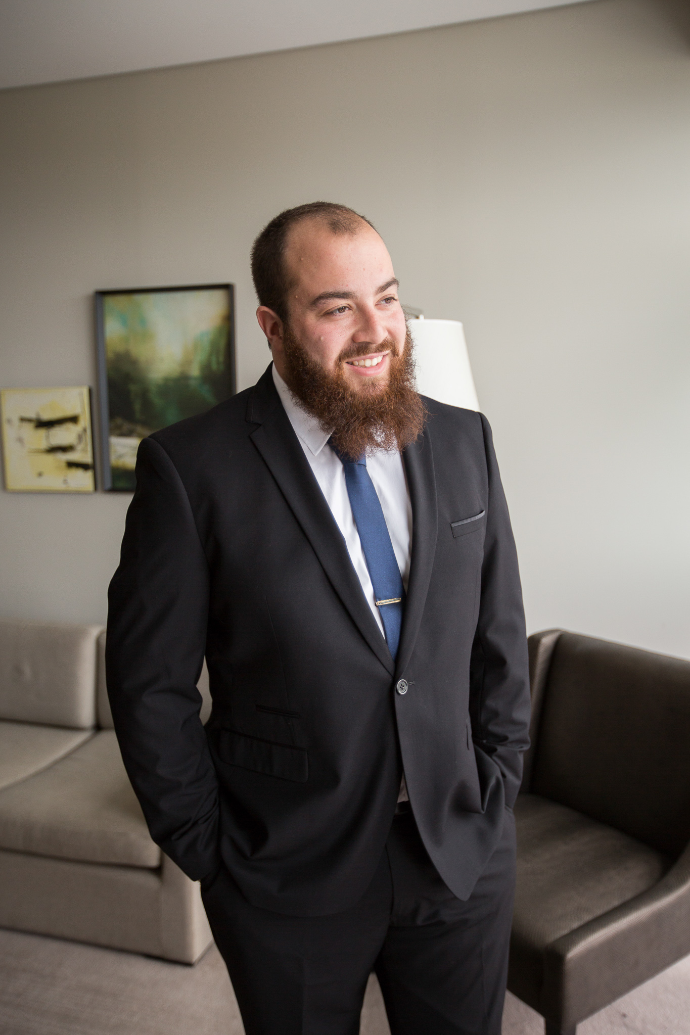 groom smiling looking out of window hands in pockets