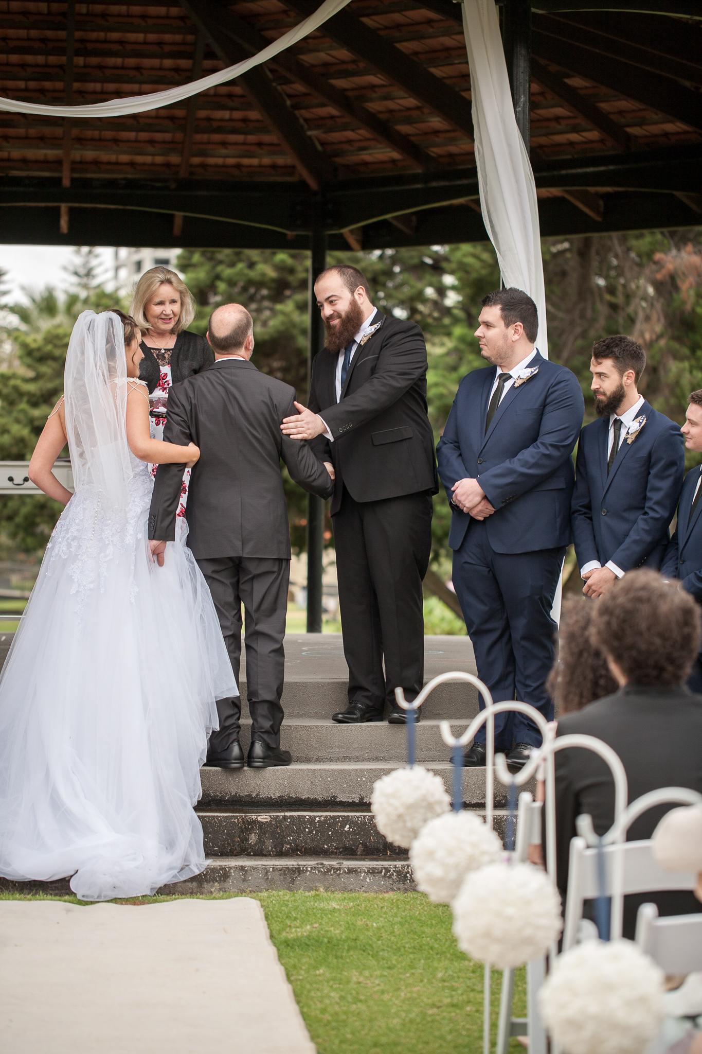 brides father shakes hand of the groom as he gives his daughter away