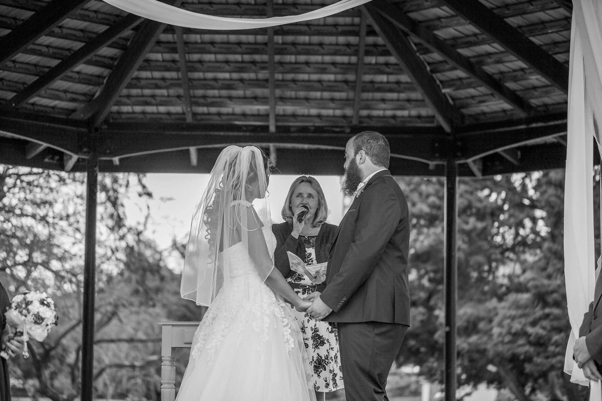 bride and groom holding hands and looking at the celebrant