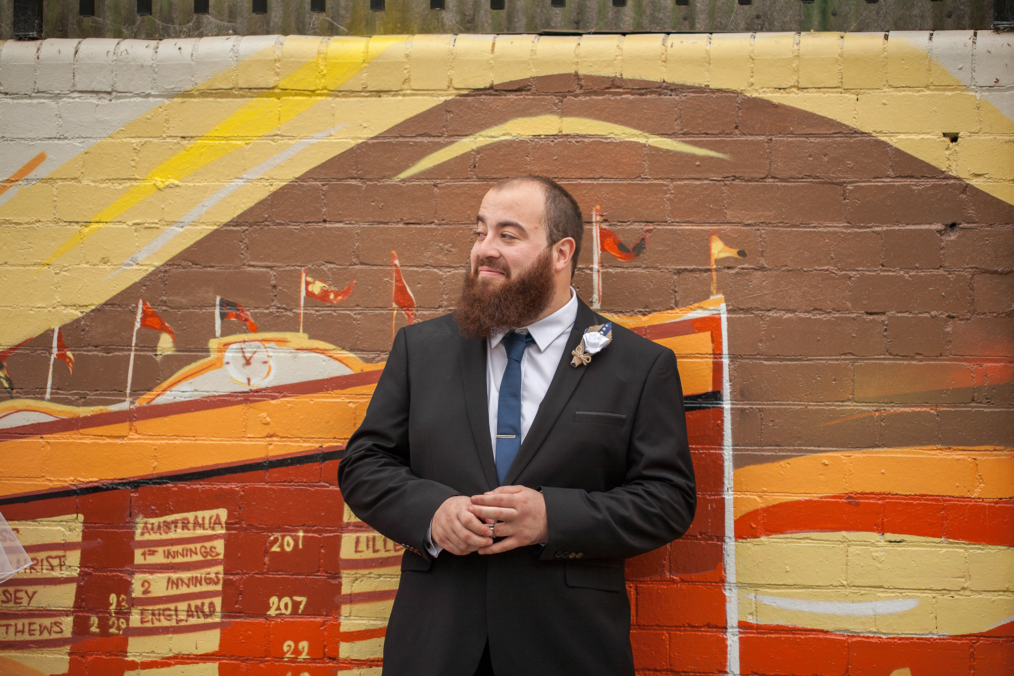 groom looking away leaning against bright wall