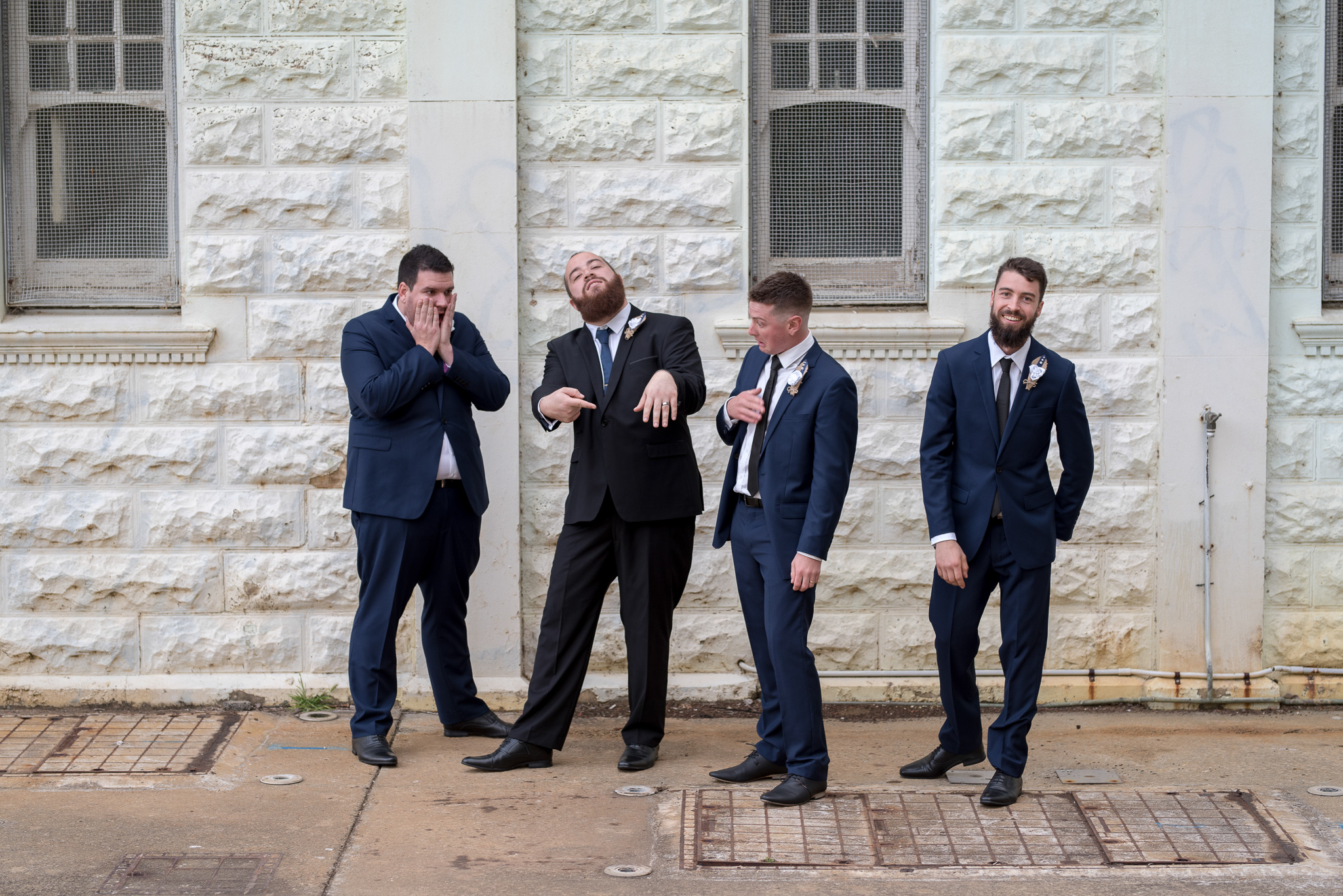 groom pointing to his ring with his groomsmen joking around him